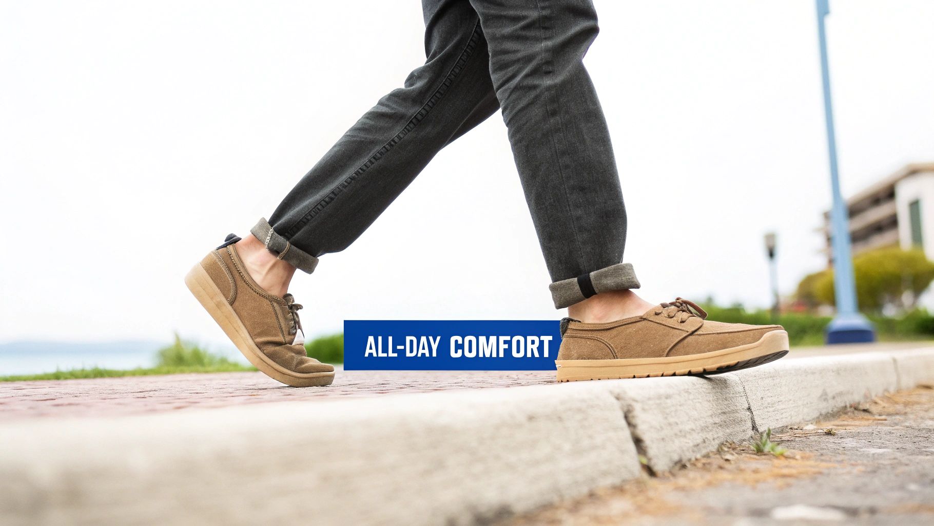 A person wearing cuffed dark jeans and brown casual shoes walks, with 'ALL-DAY COMFORT' text.