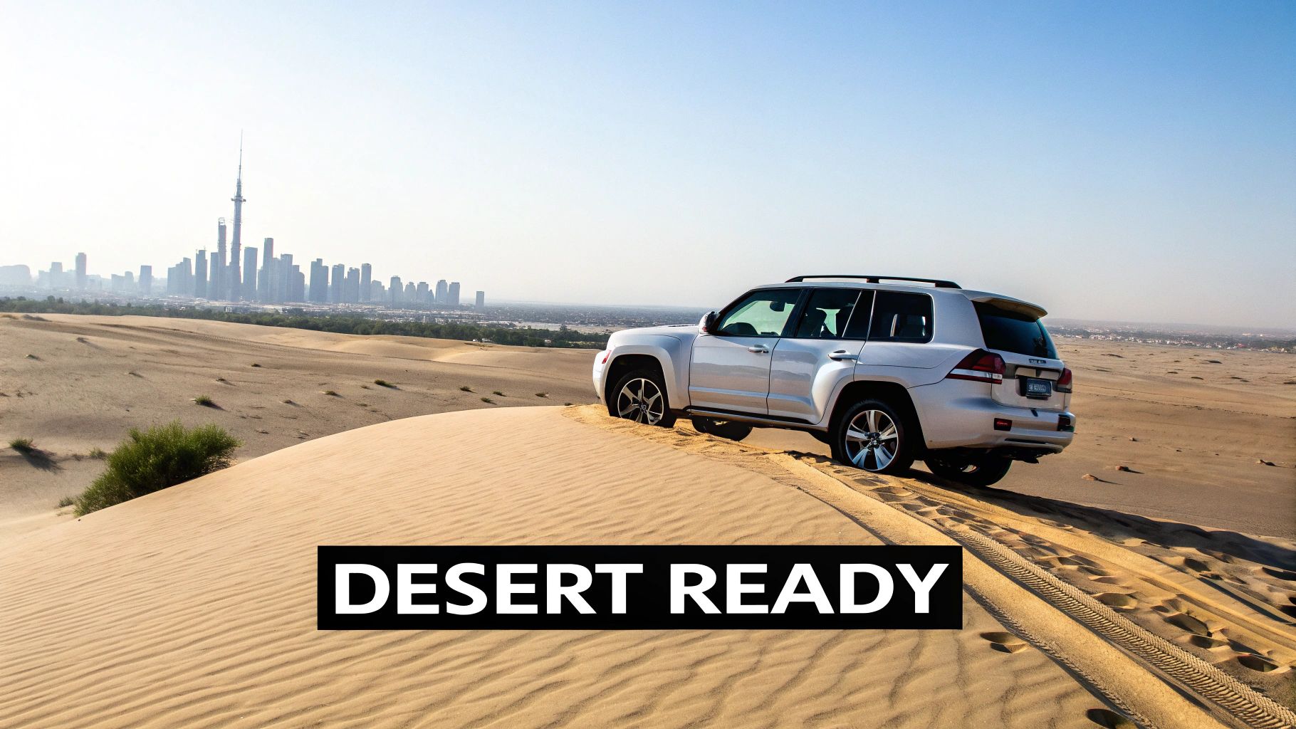 A white SUV on a sandy desert dune with the Dubai city skyline in the distant background under a clear sky.