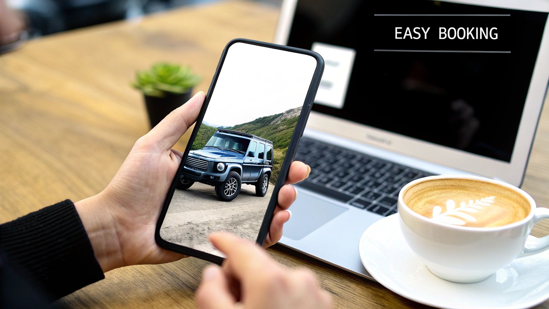 Your Guide to G63 for Rent in Dubai 2 A person holds a smartphone displaying a blue G-wagon on a road, next to a laptop and coffee cup, with “EASY BOOKING” text.