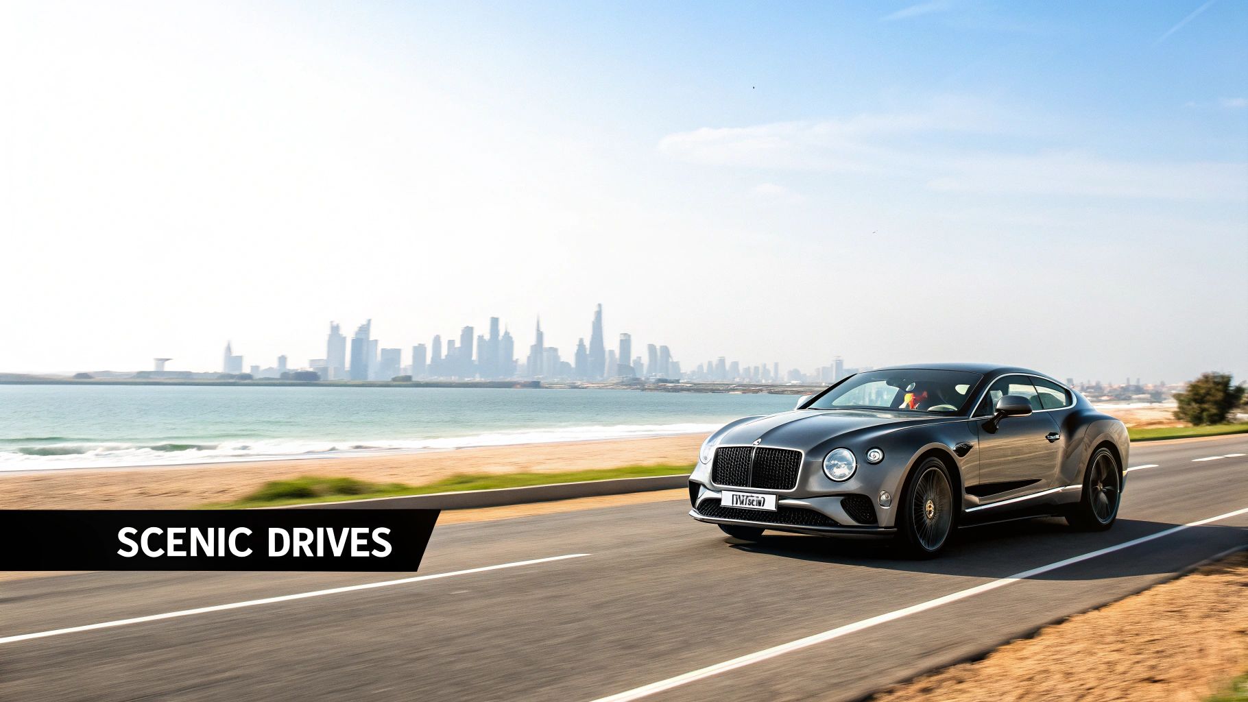 Rent a Bentley in Dubai a Guide to Ultimate Luxury 3 A luxurious grey Bentley car drives along a scenic coastal road with a city skyline in the background.