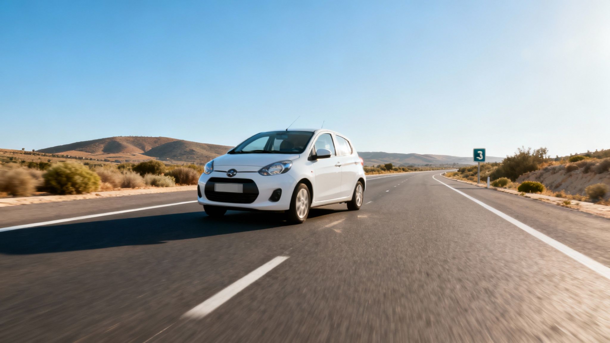 Voiture blanche sur une route de campagne sinueuse, avec des montagnes et un panneau de signalisation 3.