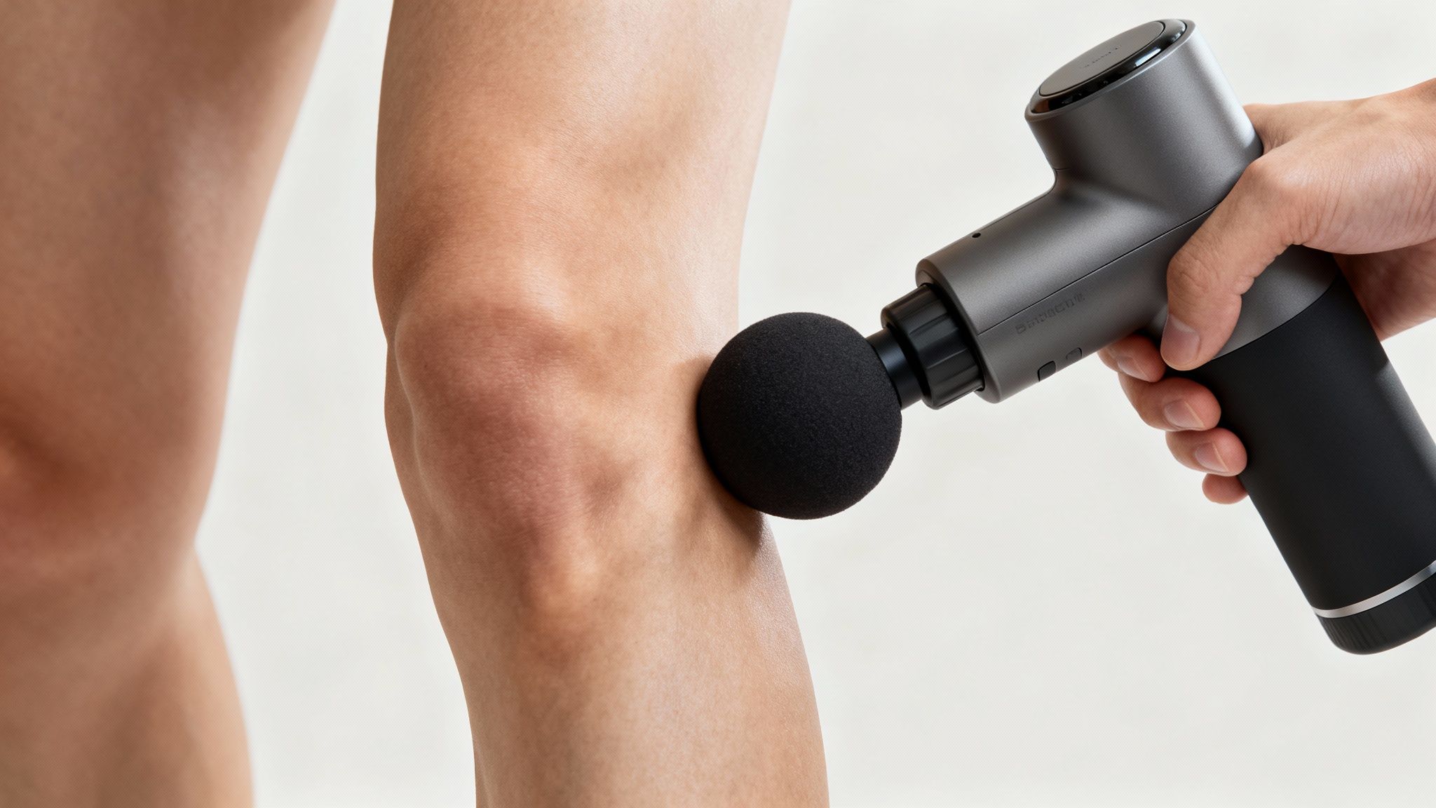 A person using the ball massage gun attachment on their leg muscles.