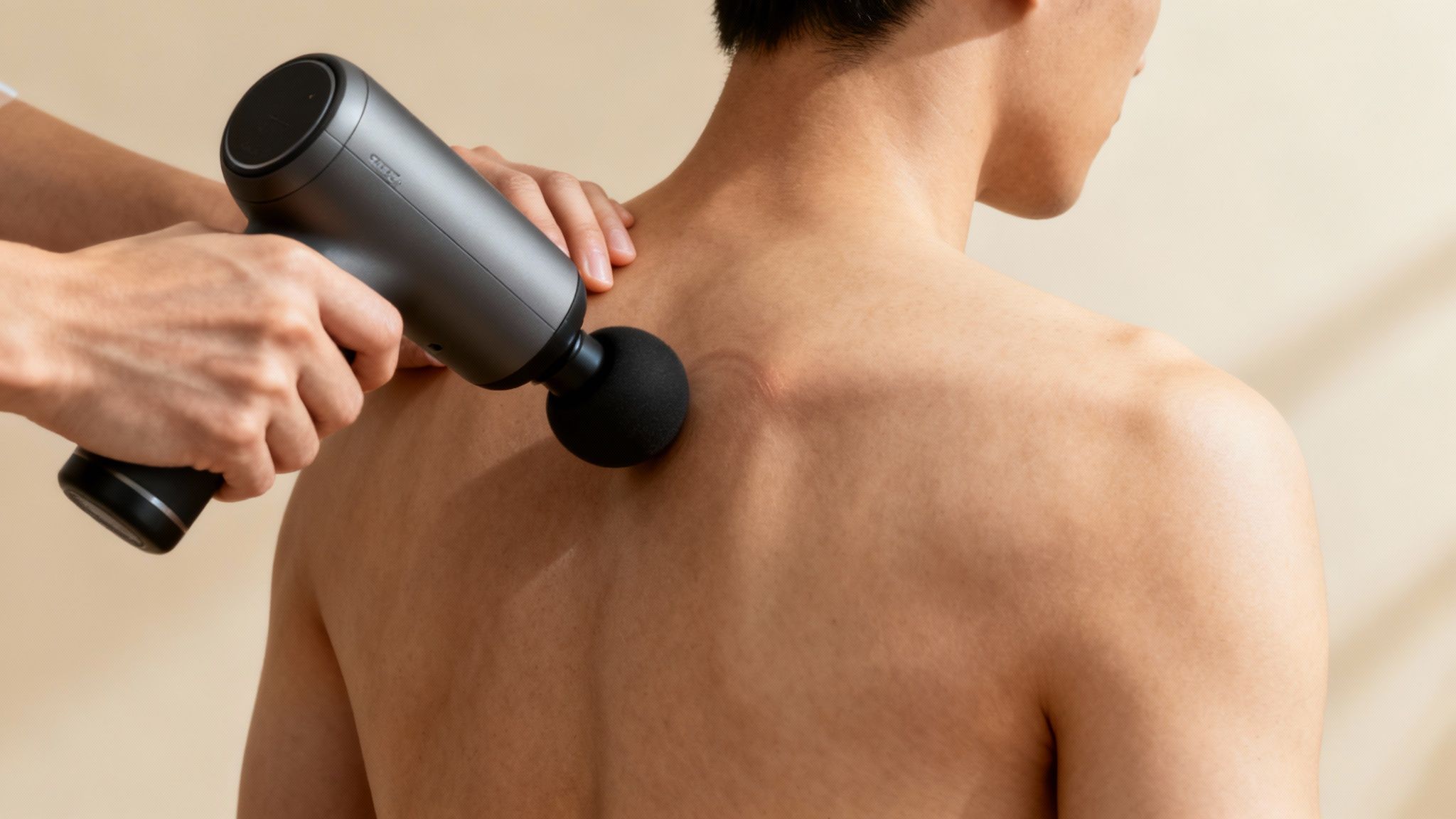 Woman using a massage gun for muscle knots on her shoulder.
