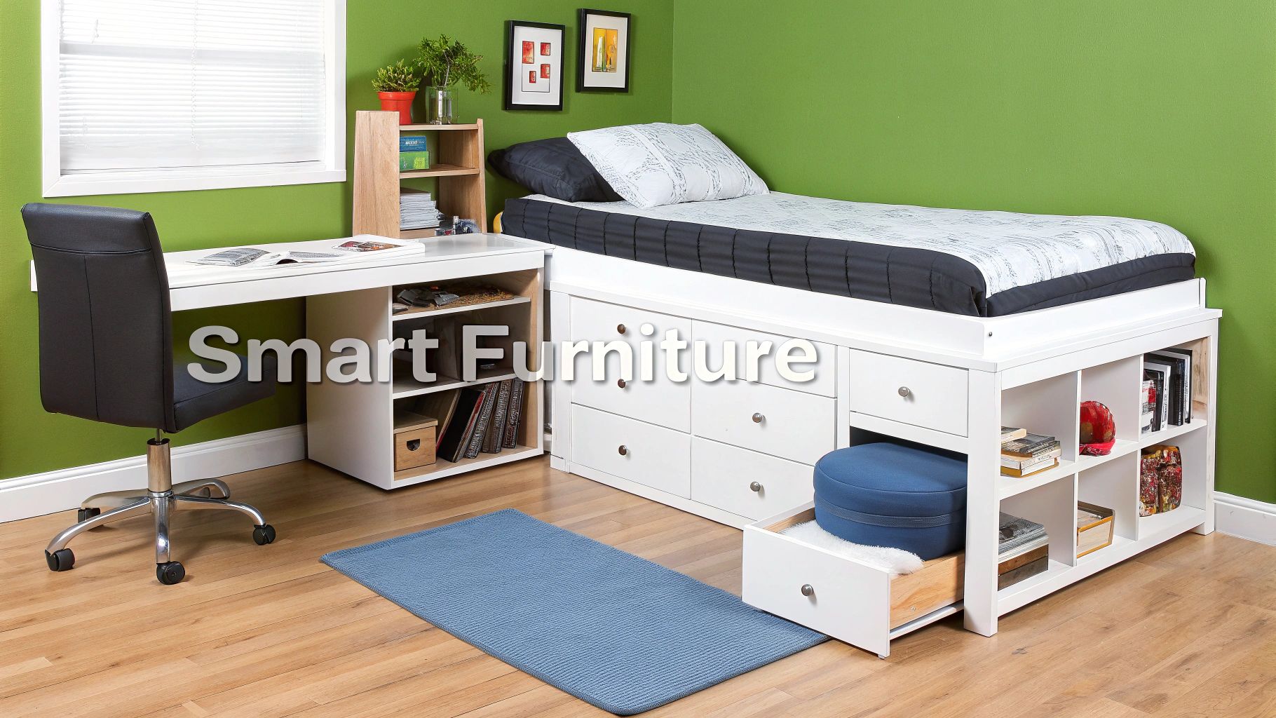 A white storage bed, matching desk, and black chair in a green bedroom with wooden floor.
