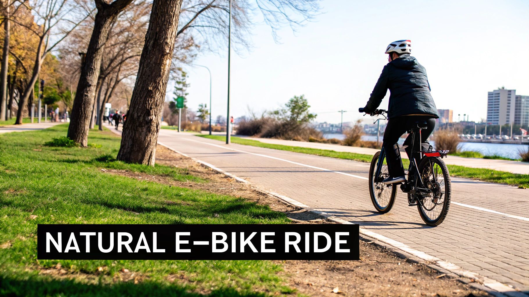 Inimene tumeda jope ja kiivriga sõidab elektriratastega mööda sillutatud jõeäärset rada.