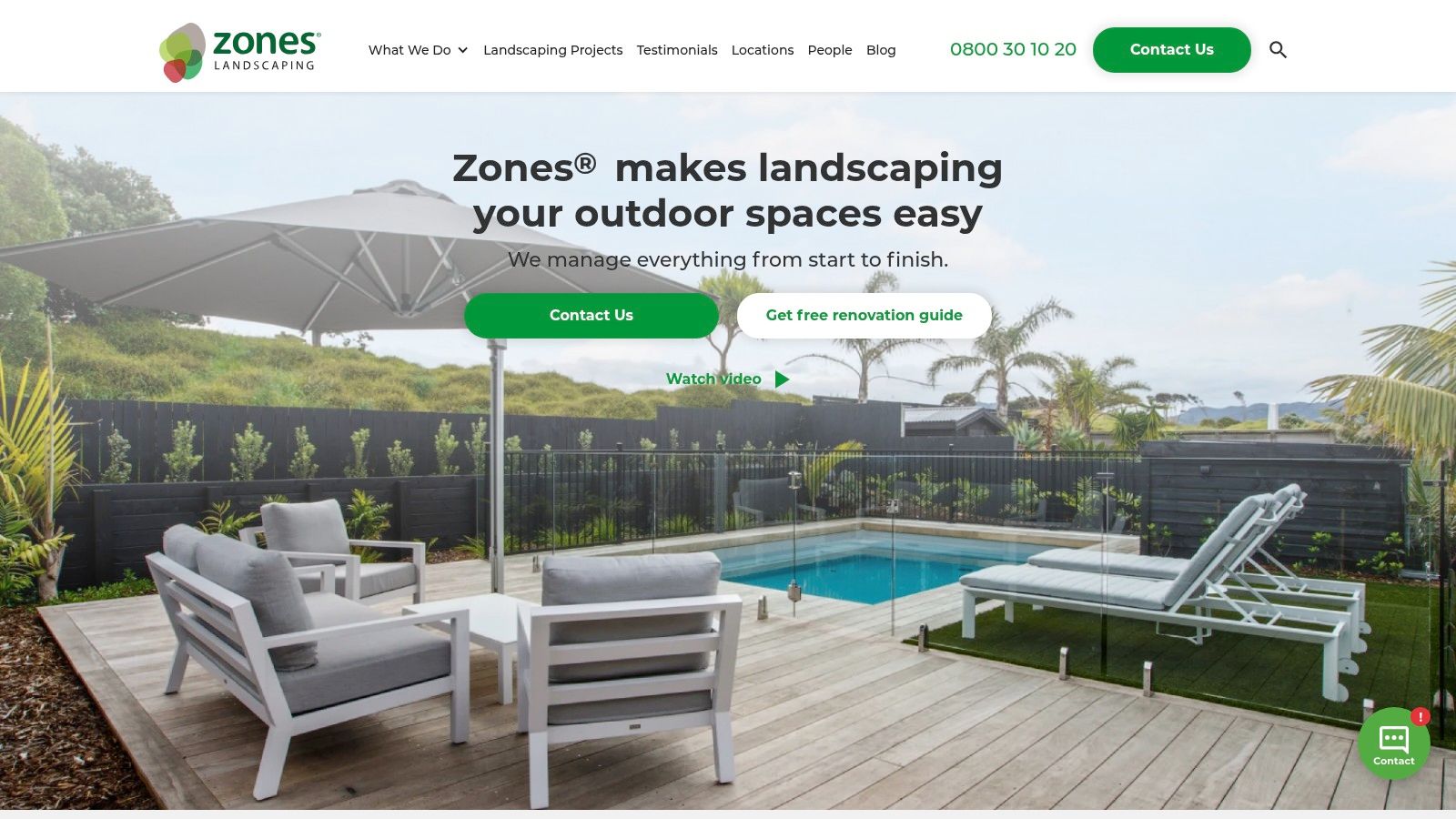 A modern backyard designed by an Auckland landscaping company, featuring a wooden deck, outdoor furniture, and lush green planting.