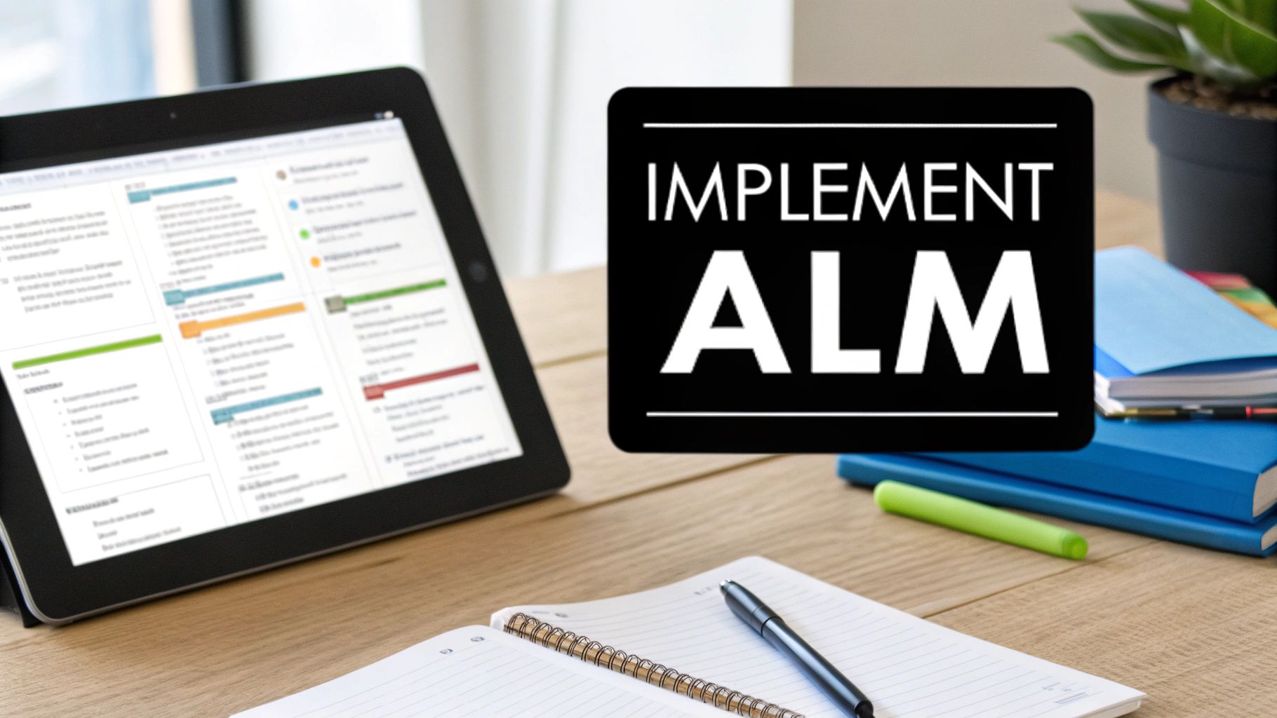 A desk with a tablet showing a software interface, an 'IMPLEMENT ALM' sign, and office supplies.