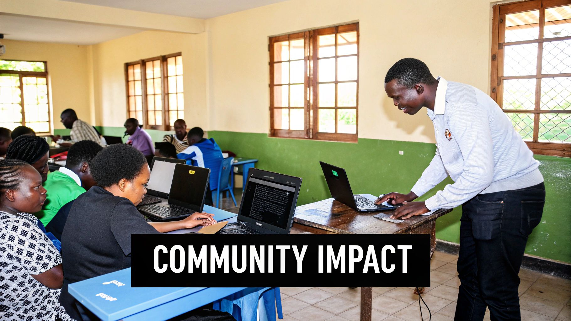 Community members learn computer skills in a classroom, with an instructor guiding on laptops.