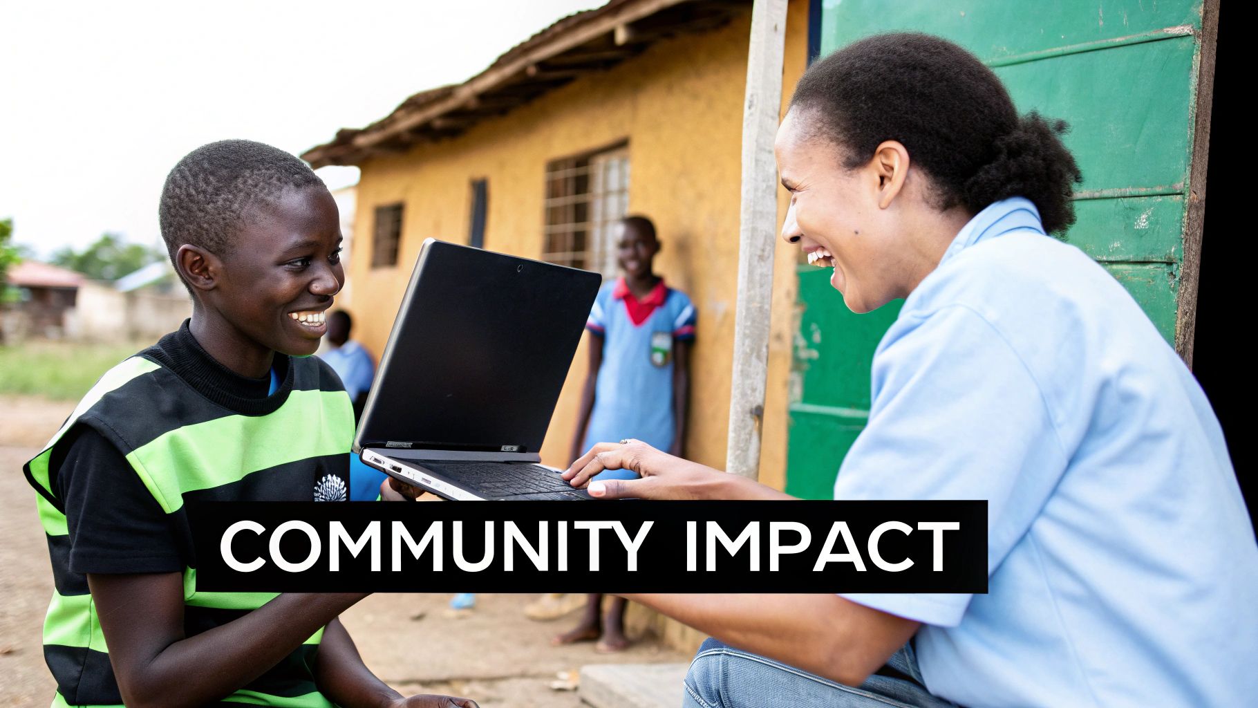 An adult and a child happily interacting with a laptop in an outdoor community setting.
