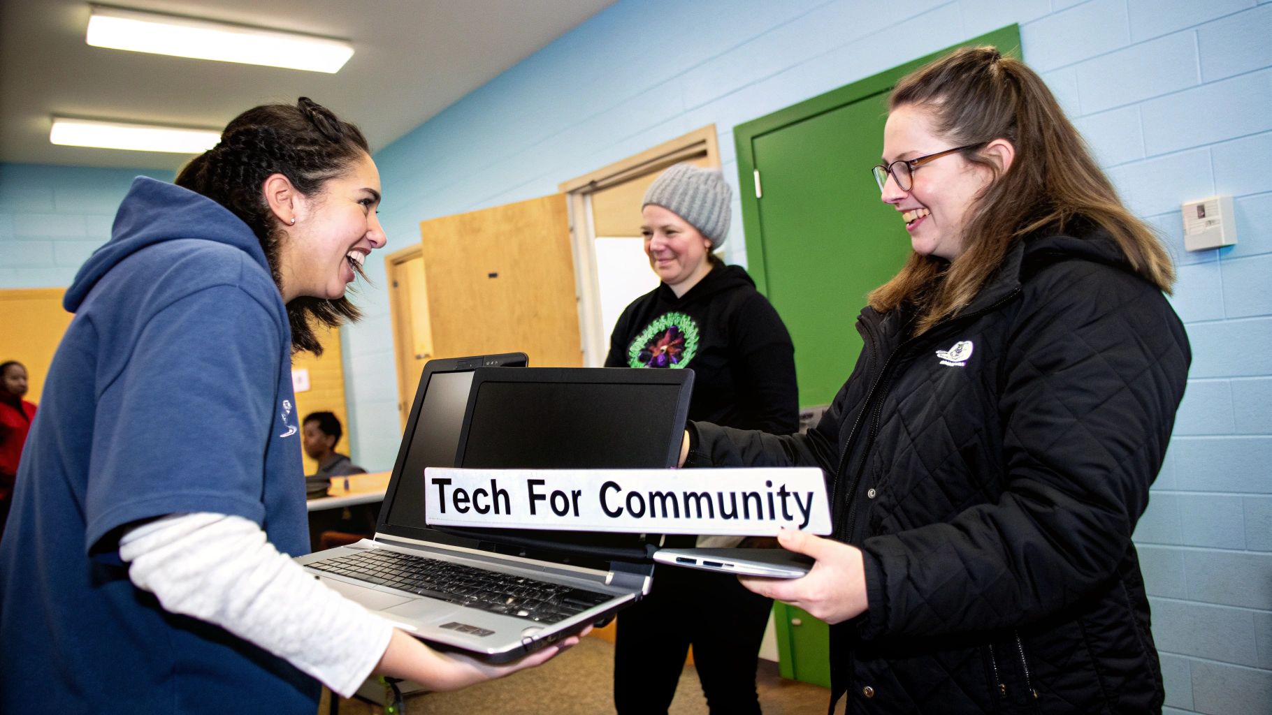Two smiling women exchange laptops at a 'Tech For Community' event, promoting digital access.