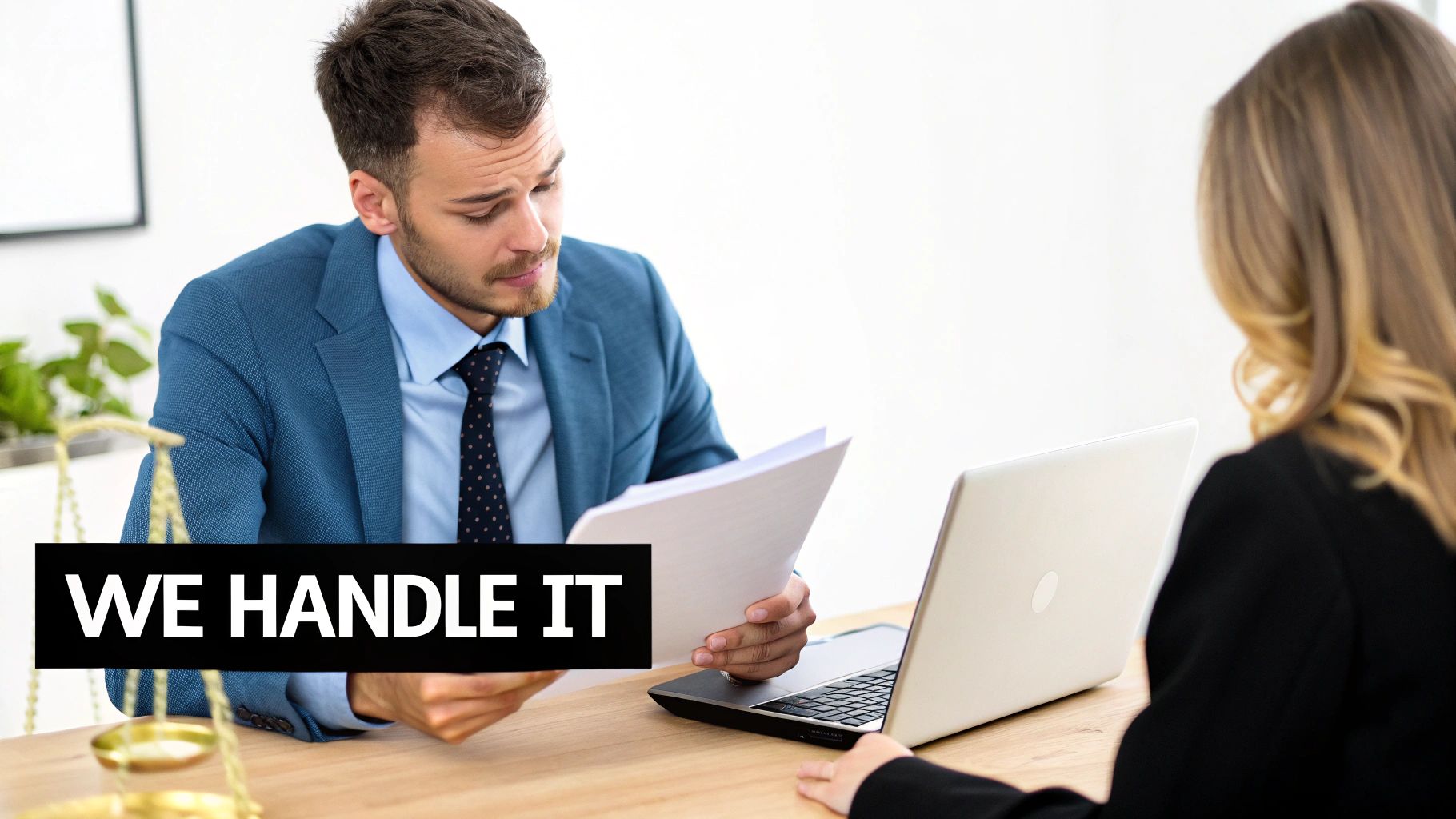 A male attorney in a blue suit reviews documents with a female client, scales of justice visible.