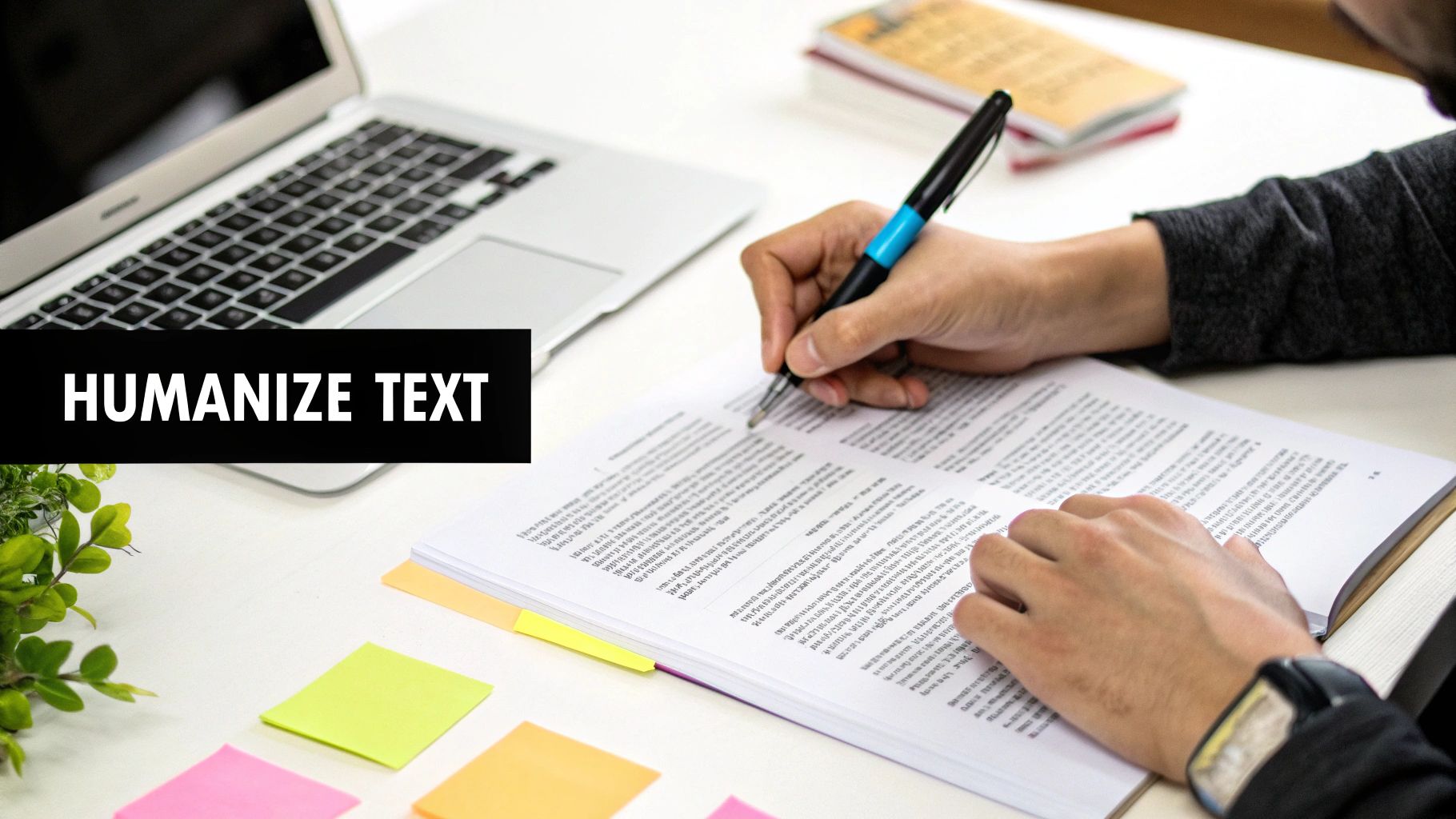 A person's hands write on a document with a pen, a laptop, and sticky notes visible, featuring text 'HUMANIZE TEXT'.