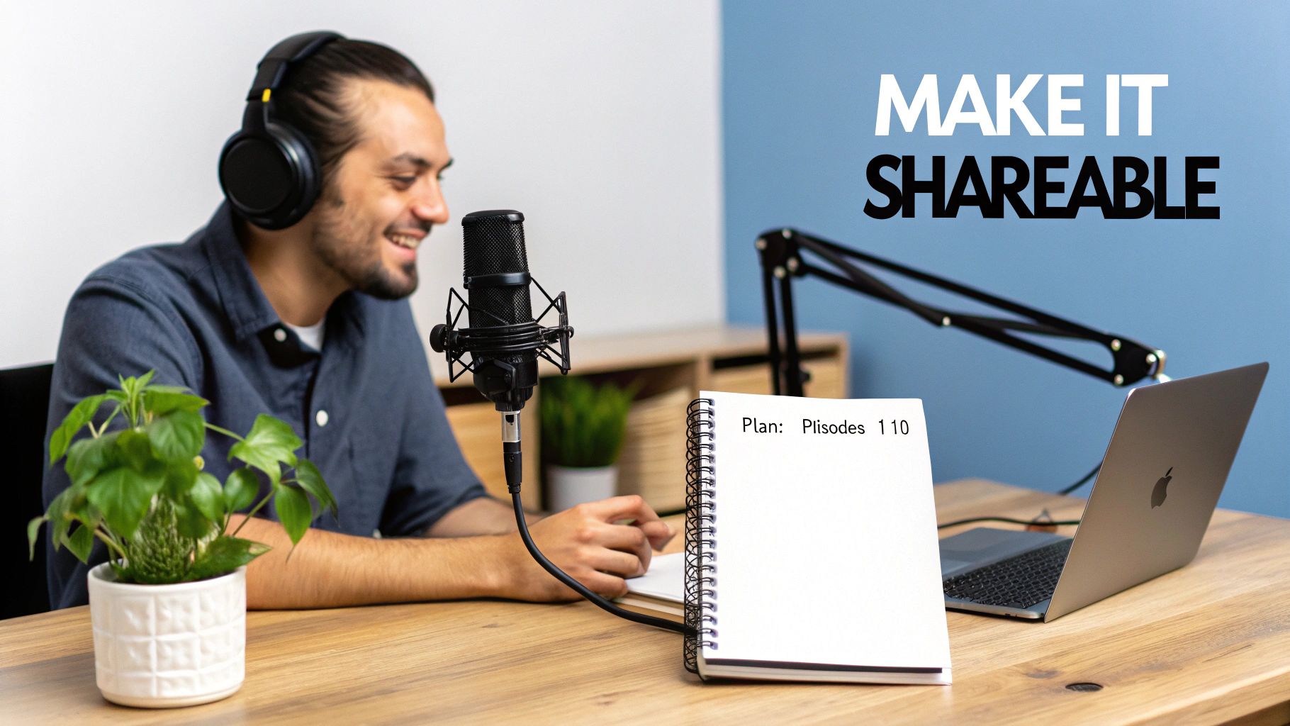 A man with headphones smiles while recording a podcast with a microphone, laptop, and notebook.