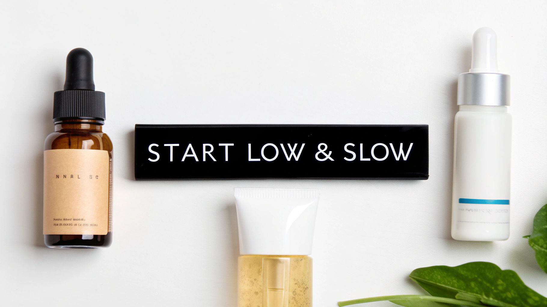 Various skincare products including serums and a cream, with a sign saying 'START LOW & SLOW' on a white background with green leaves.