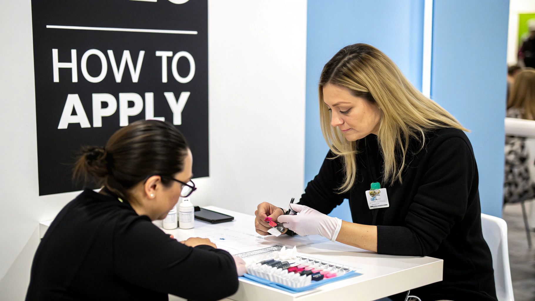 Two women at a white table, one demonstrating how to apply press-on nails, with a 'HOW TO APPLY' sign.