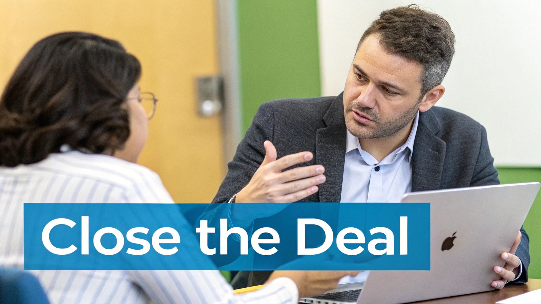 A man in a suit jacket gestures while speaking to a colleague, holding a laptop, with 'Close the Deal' text overlay.