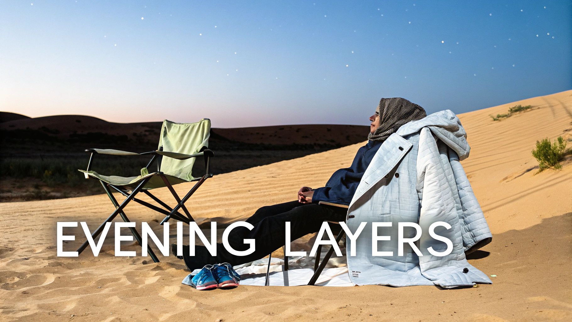 A person wearing a hijab and warm coat sits in a desert camping chair, stargazing at dusk.