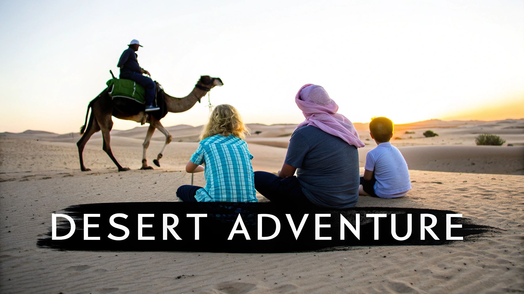 A family with children sitting on desert dunes, watching a camel and rider at sunset.