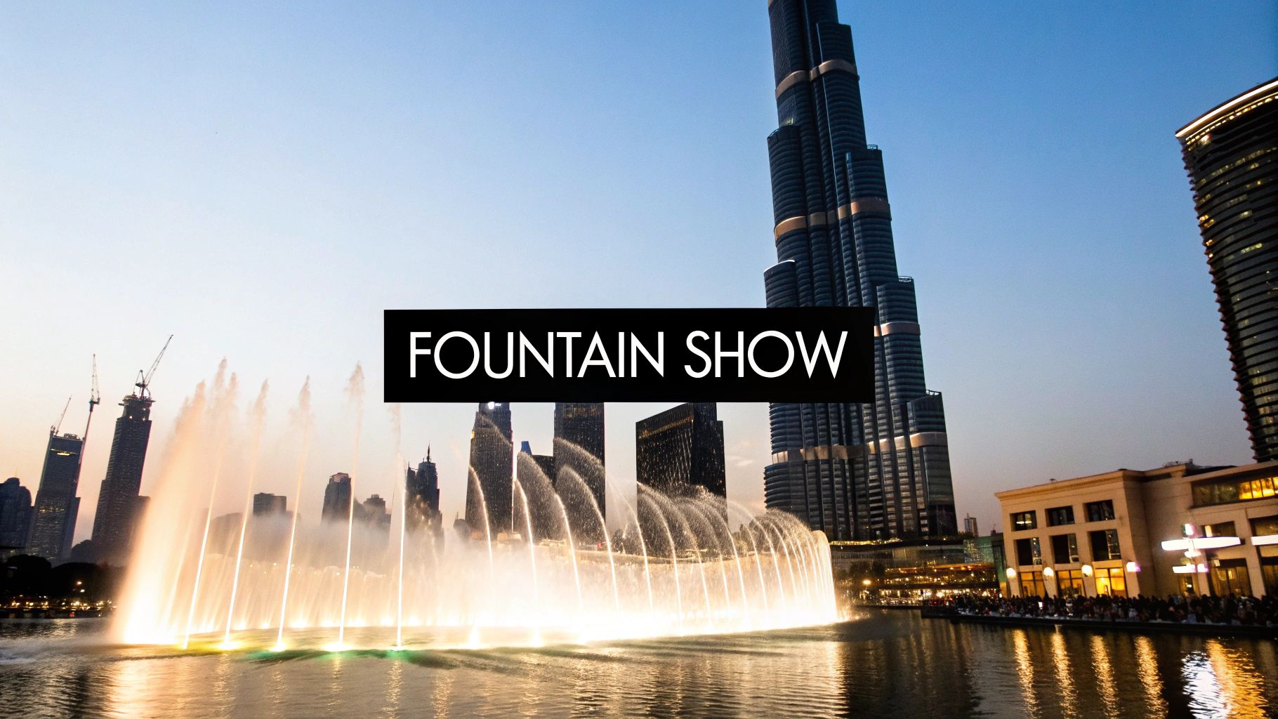 A vibrant fountain show with illuminated water jets in front of tall skyscrapers like Burj Khalifa at dusk.