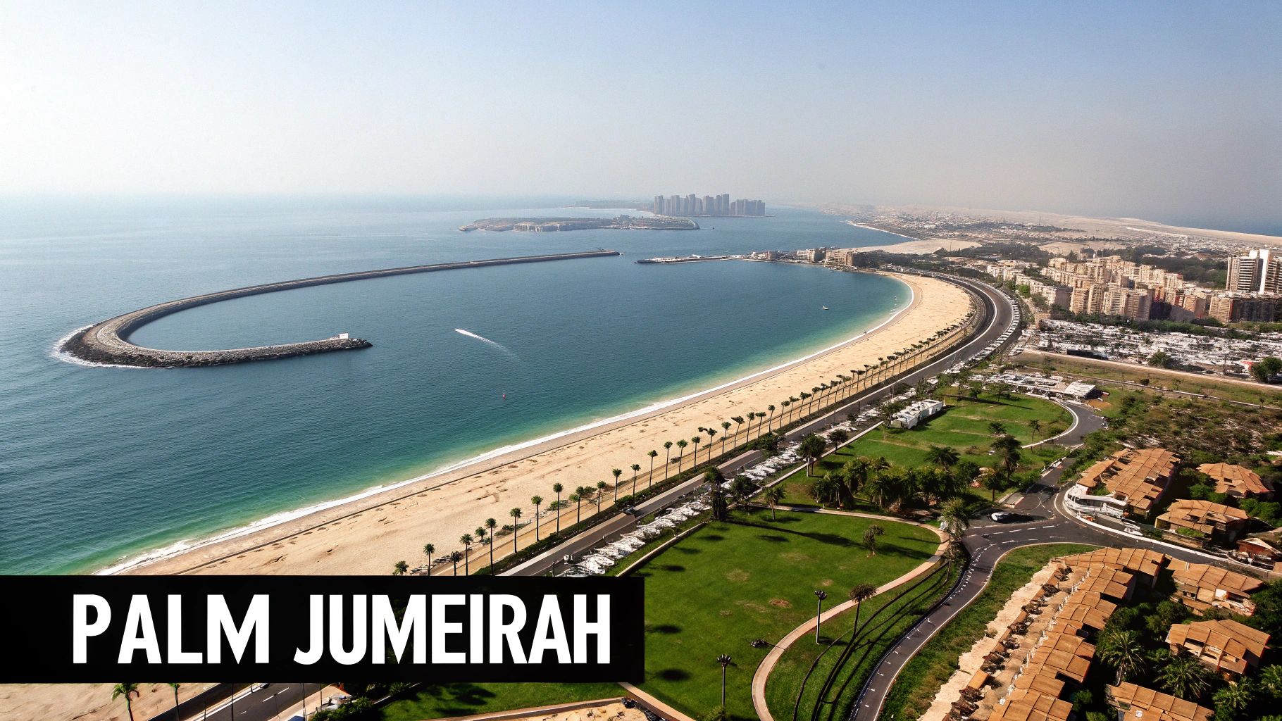 Aerial view of Palm Jumeirah, Dubai, showing its iconic crescent breakwater, beach, and cityscape.