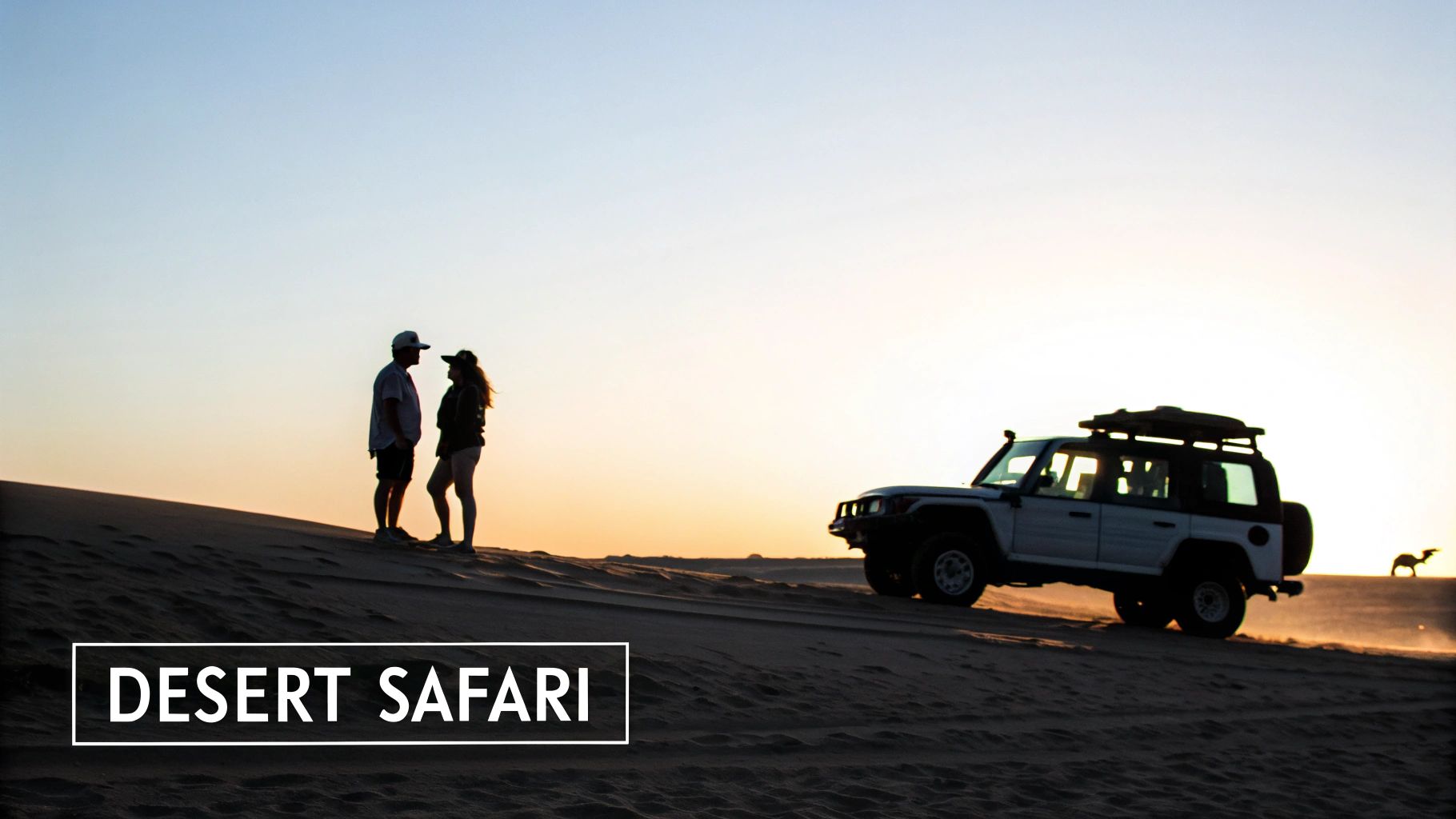 A couple stands on a sand dune with a safari SUV and a camel silhouette at sunset.