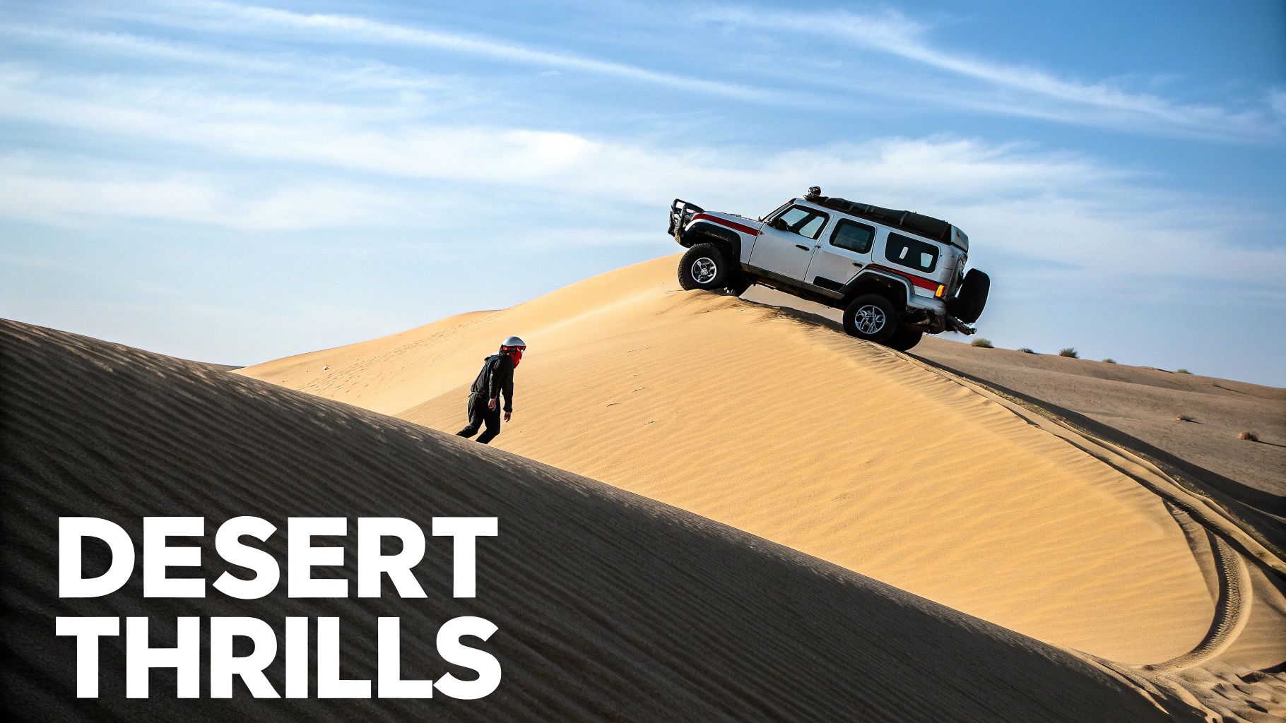 An adventurer walks a steep desert sand dune while an off-road vehicle drives nearby.