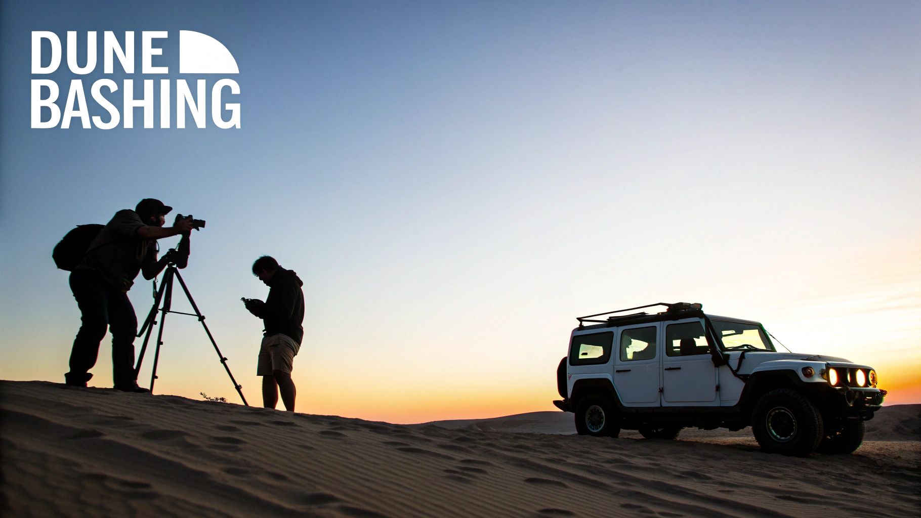 Two photographers on a sand dune at sunset with an off-road SUV, enjoying a desert safari.
