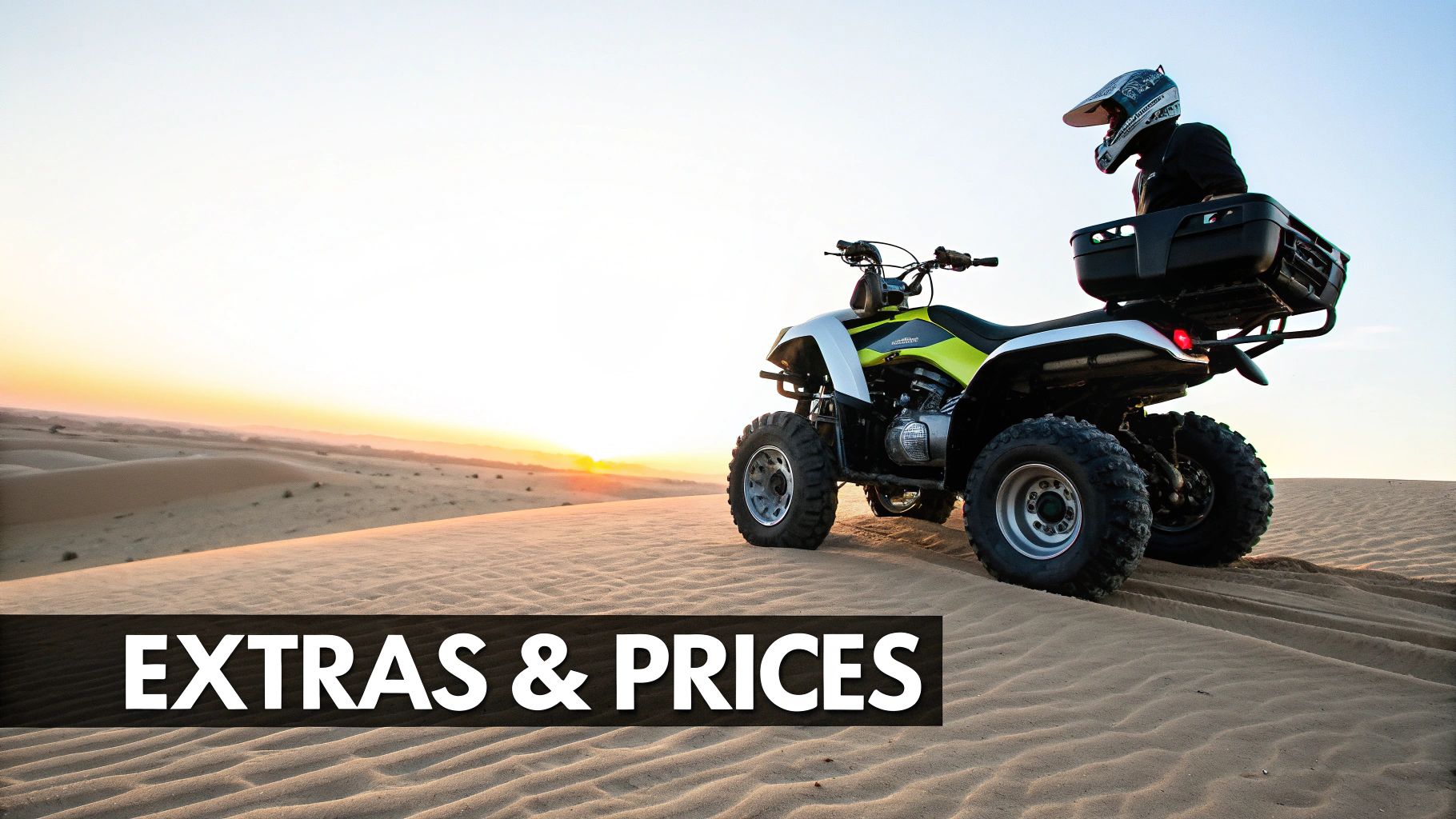 A person in a helmet rides a quad bike on sand dunes during a beautiful desert sunset.
