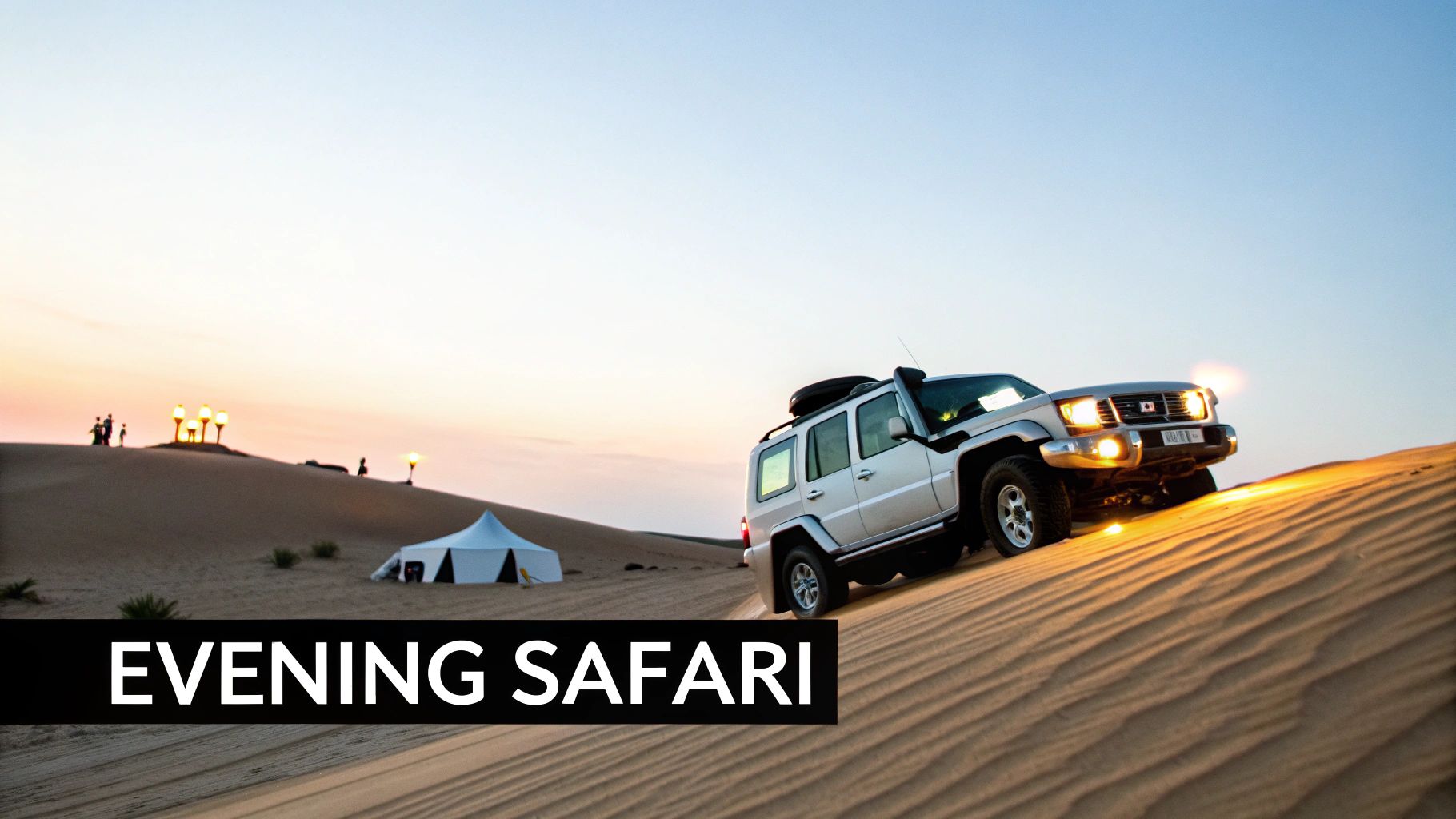 A silver SUV drives up a sandy dune during an evening desert safari with a camp setup.