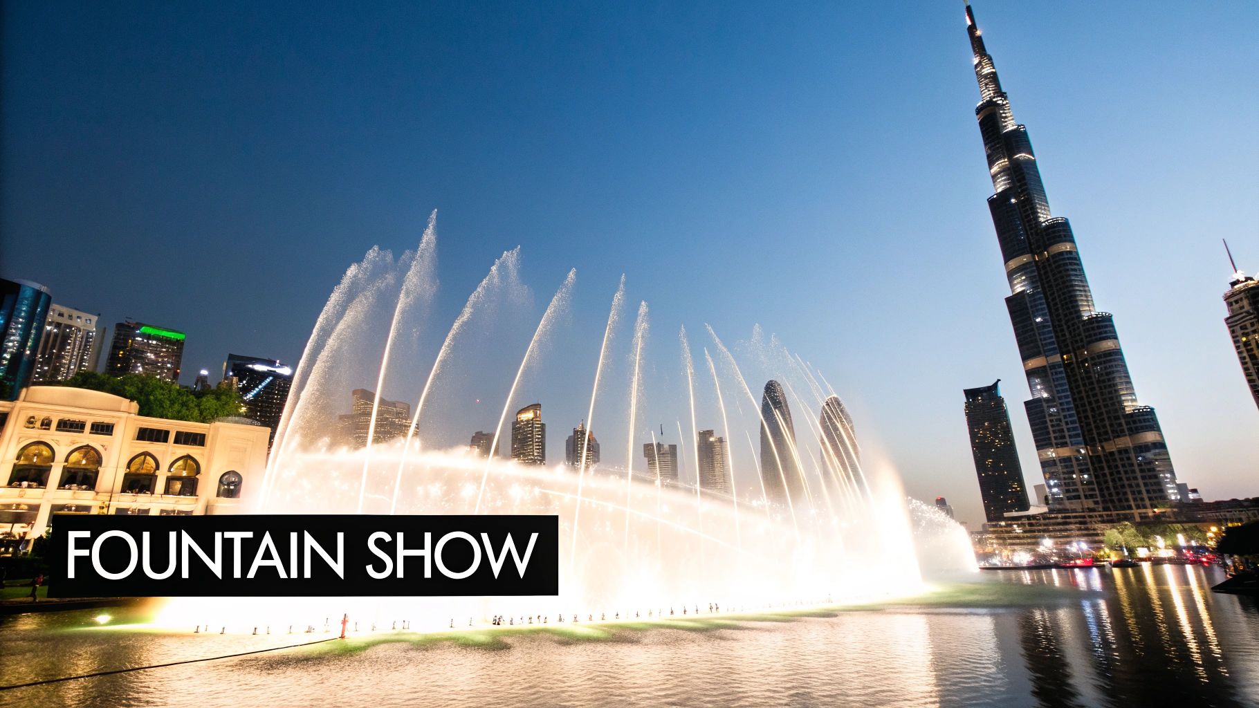 The Dubai Fountain show in full display with water jets and lights in front of the illuminated Burj Khalifa.