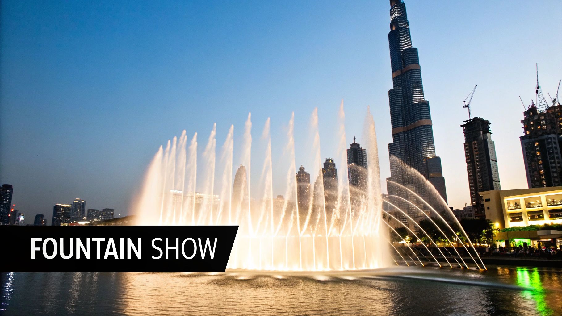A stunning evening view of the Dubai Fountain show with Burj Khalifa and illuminated city skyscrapers.