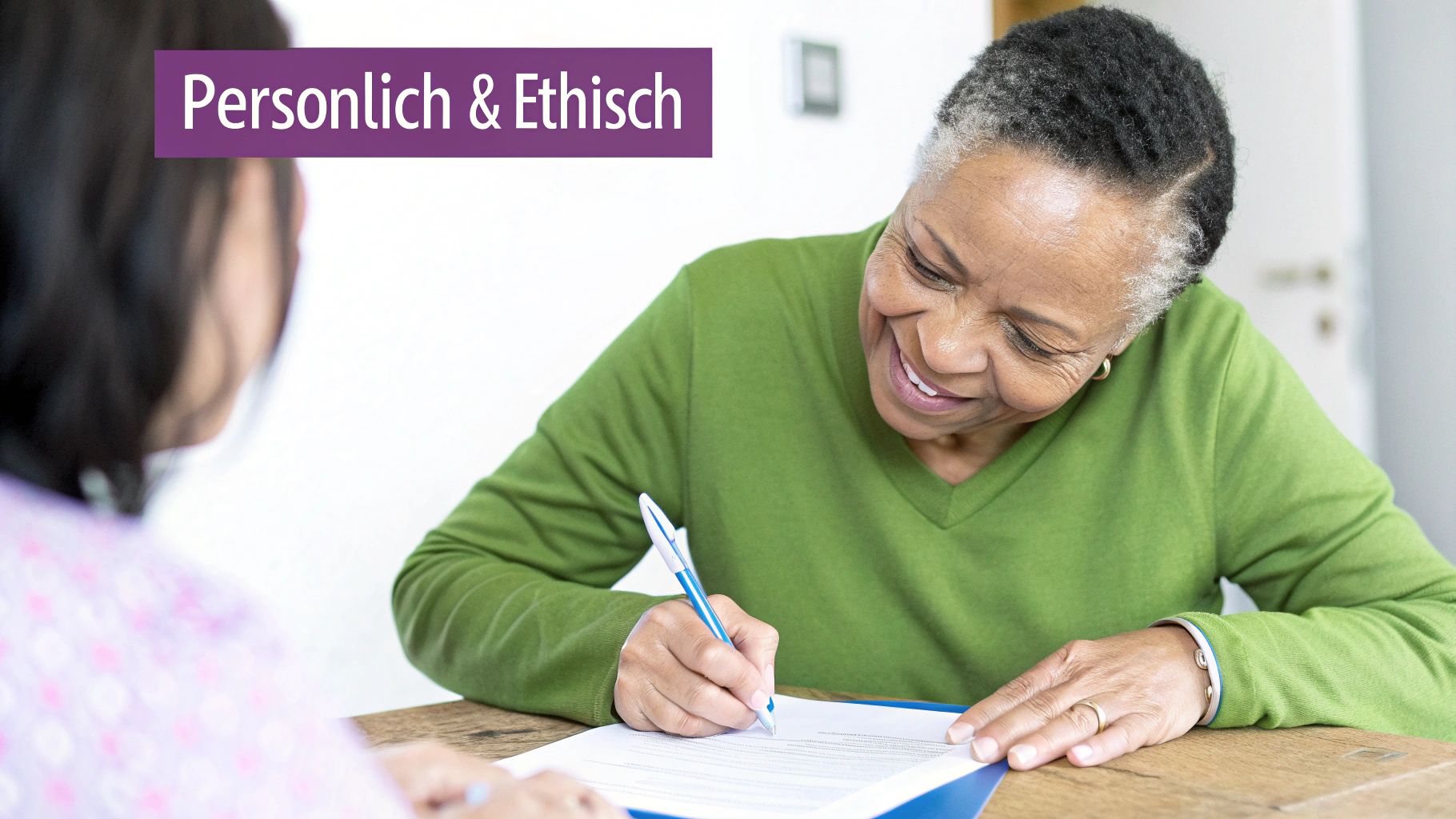 Ältere schwarze Frau lächelt und unterschreibt ein Dokument an einem Tisch, während eine andere Person zuschaut.