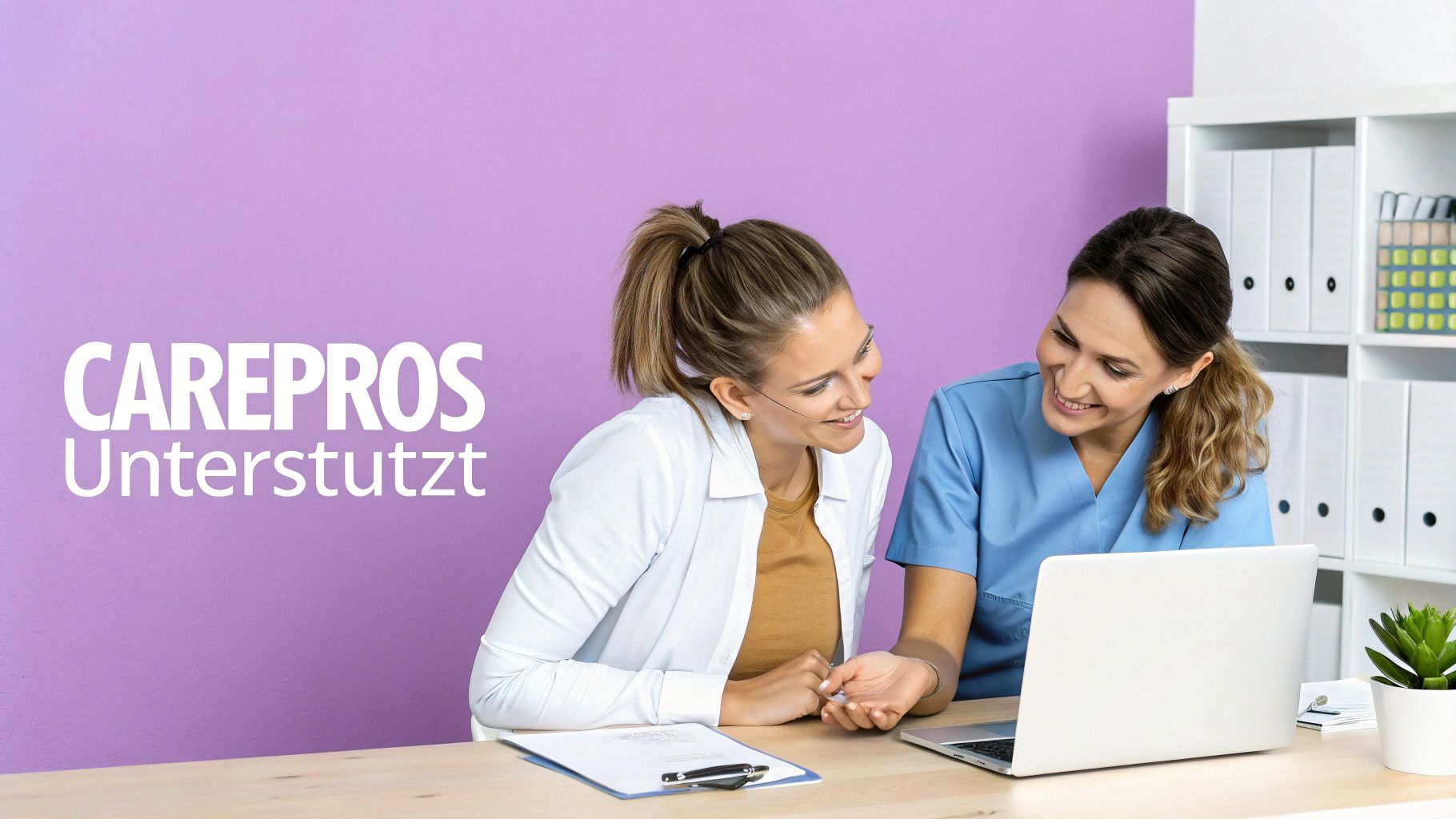 Zwei lächelnde Frauen, möglicherweise Pflegekräfte, besprechen sich an einem Schreibtisch mit Laptop.