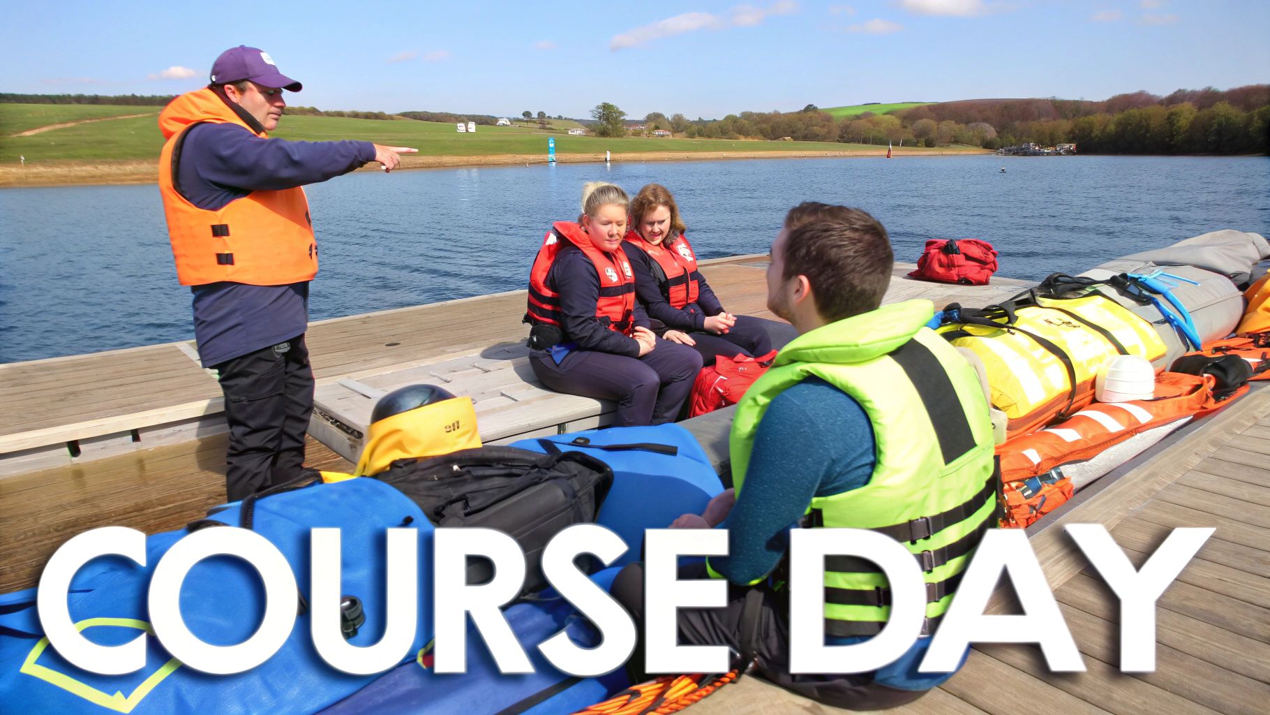 Instructor pointing on a dock to students wearing life jackets, preparing for a water course.