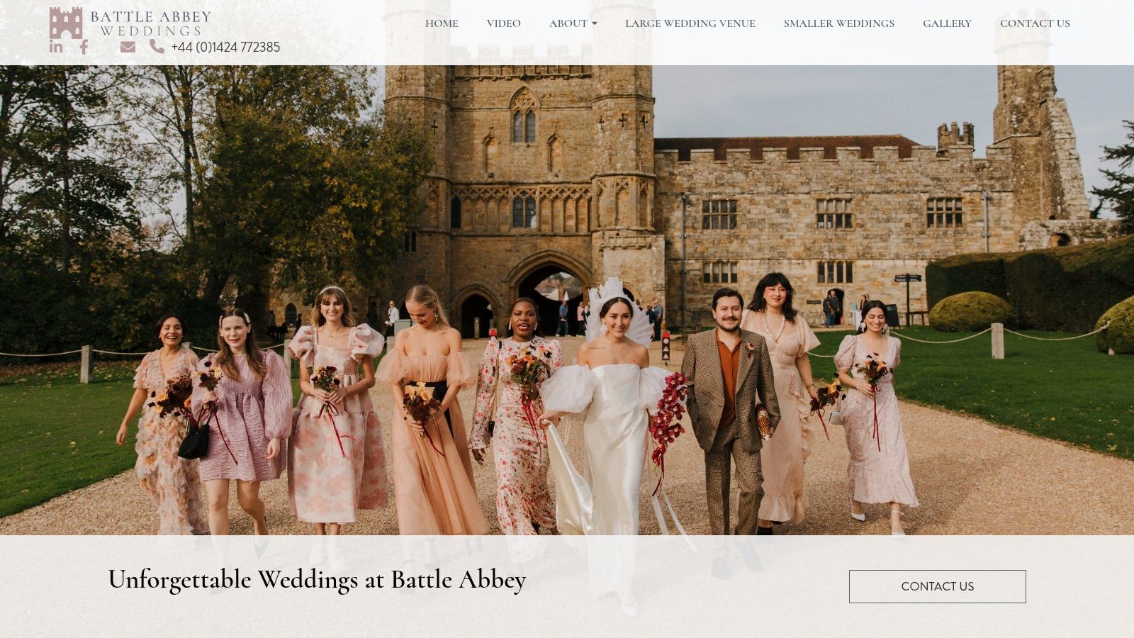 A wedding party stands on the historic grounds of Battle Abbey, with ancient ruins in the background.