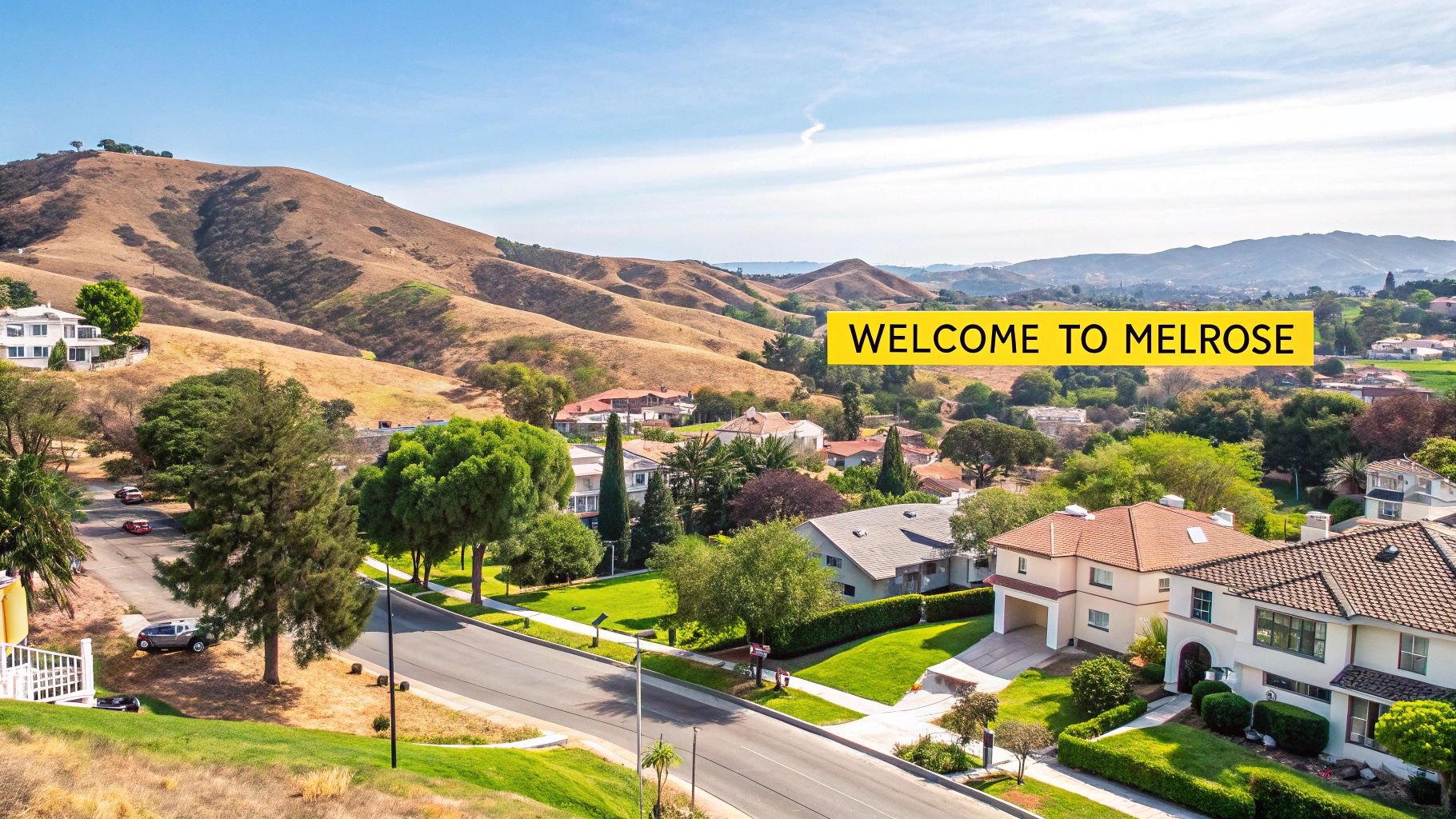 Aerial view of Melrose, a scenic suburban neighborhood with houses and streets backed by dry hills under a blue sky.