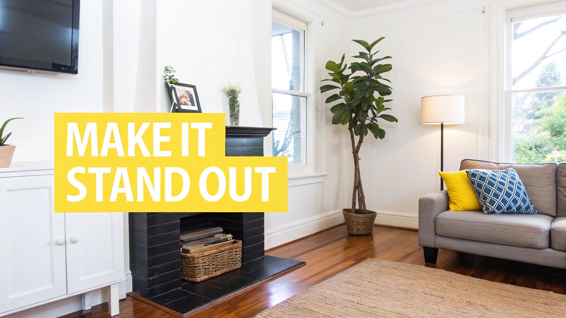 A cozy living room with a fireplace, grey couch, a large plant, and wooden floors.