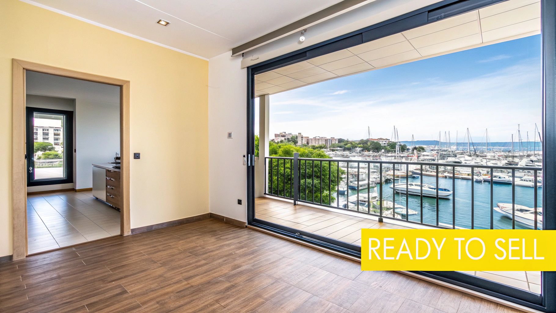 A modern room with a balcony showcasing a scenic marina view filled with boats and a distant cityscape.