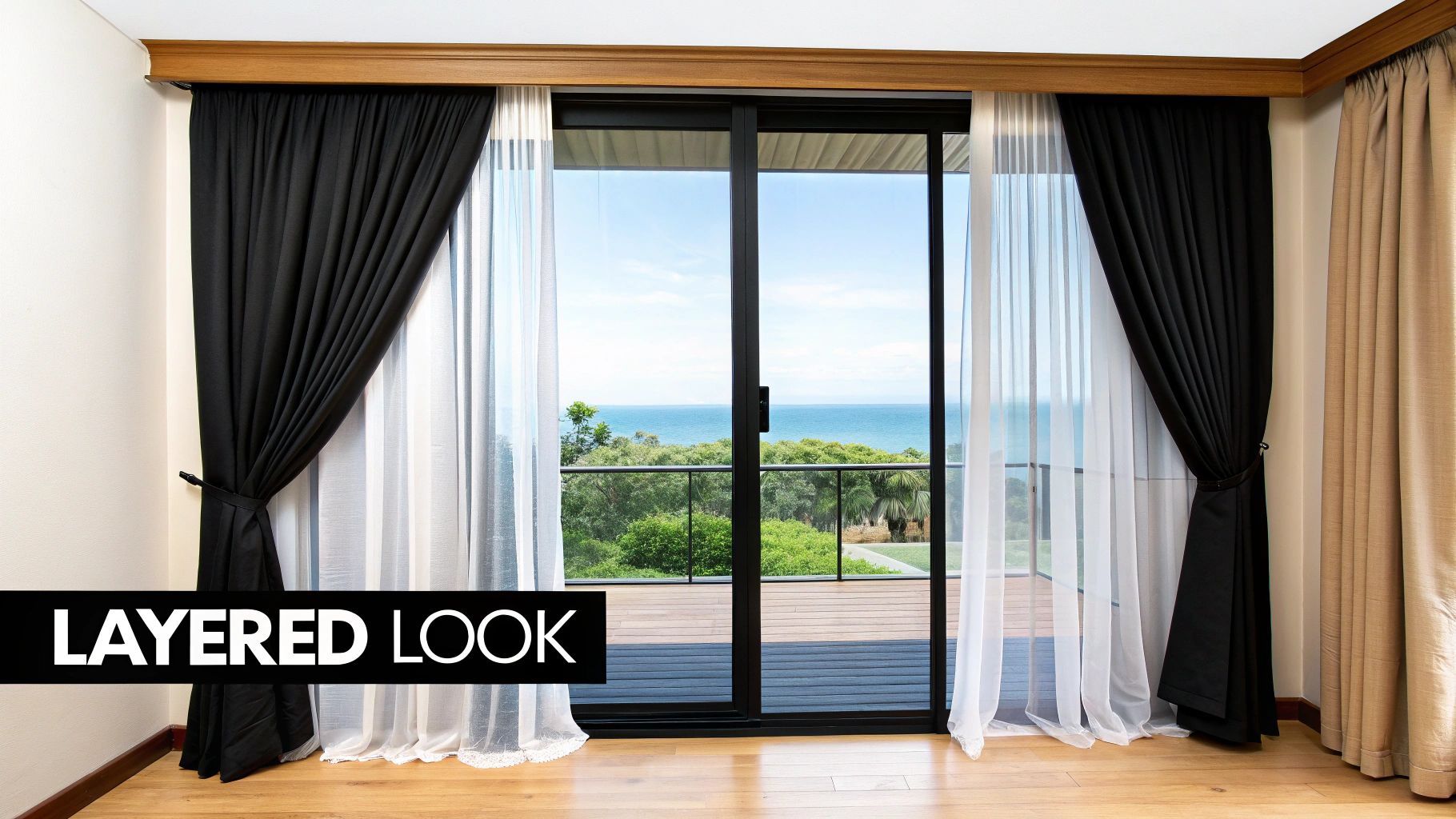 A room with sliding glass patio doors, featuring layered black and white curtains and an ocean view.