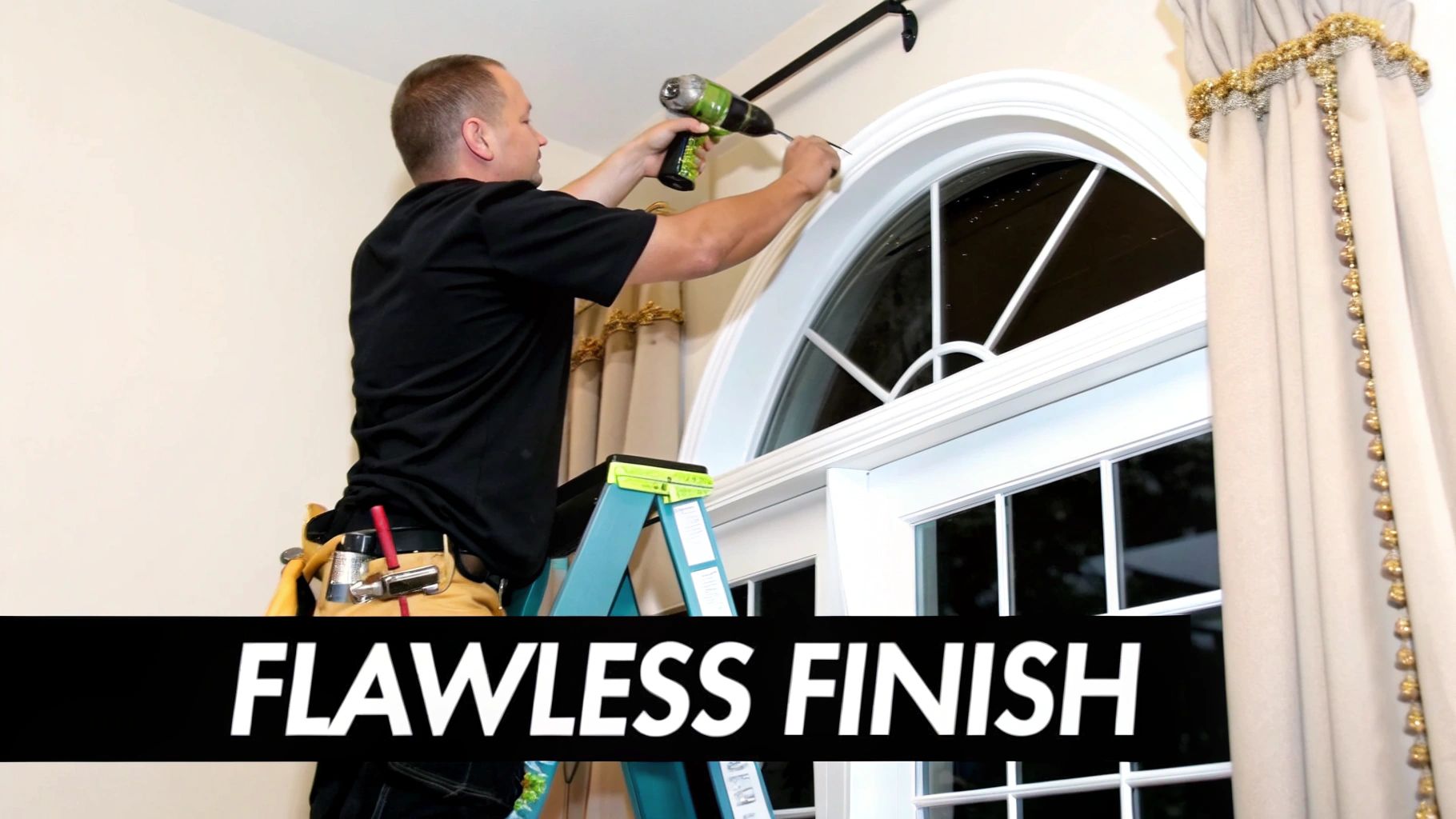 A man on a ladder installing a curtain rod above an arched window with a power drill.