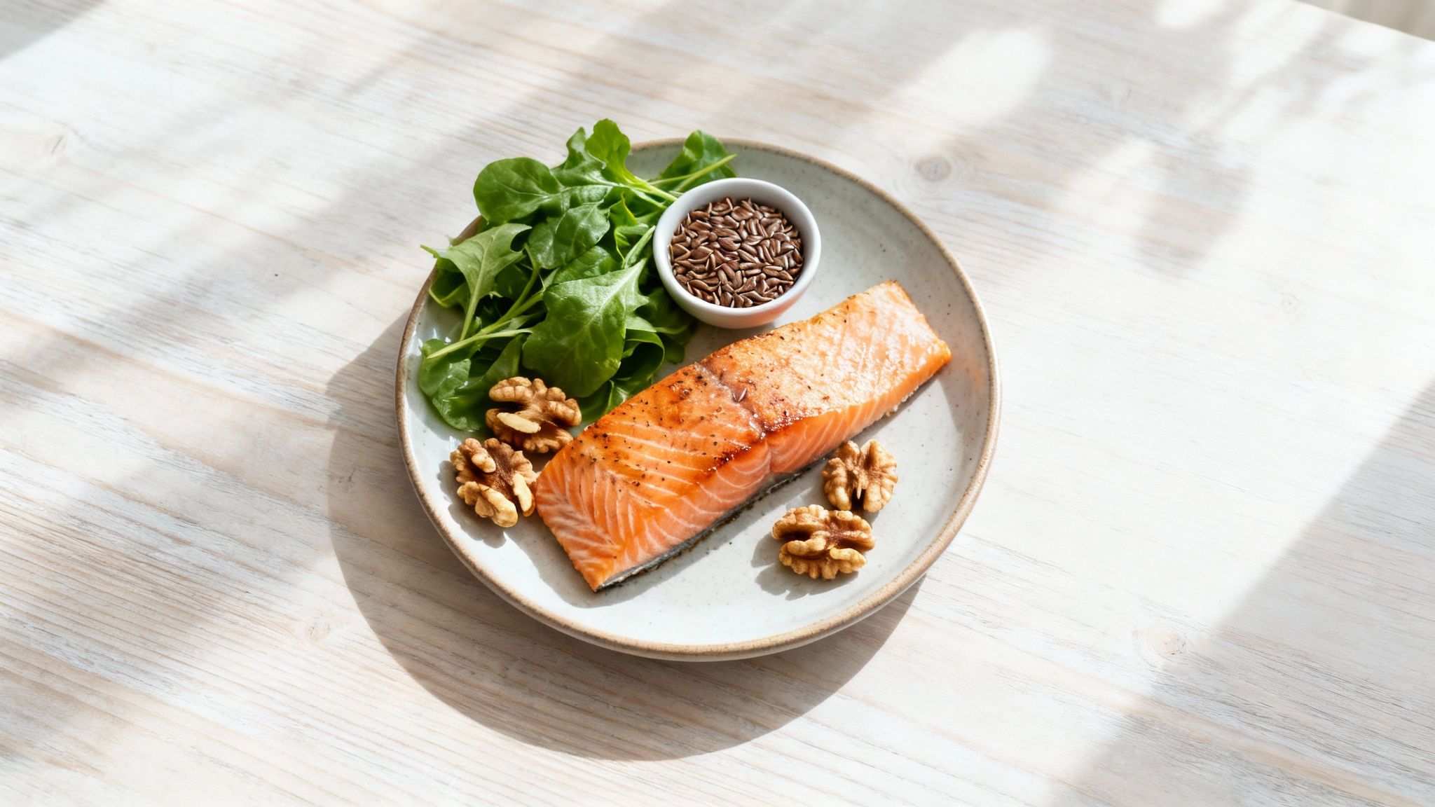 Ein Teller mit gegrilltem Lachs, frischem grünem Salat, Walnüssen und Leinsamen auf einem Holztisch.