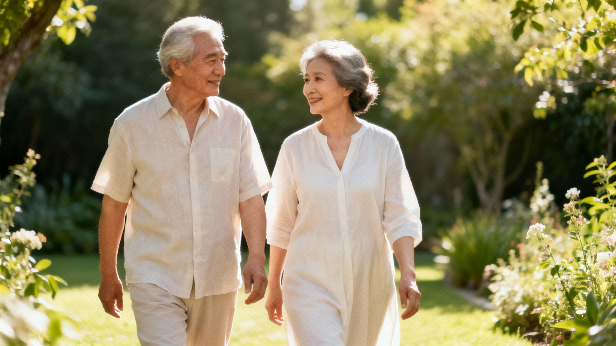 Glückliches älteres asiatisches Paar spaziert lächelnd und hält Händchen in einem sonnigen Garten.