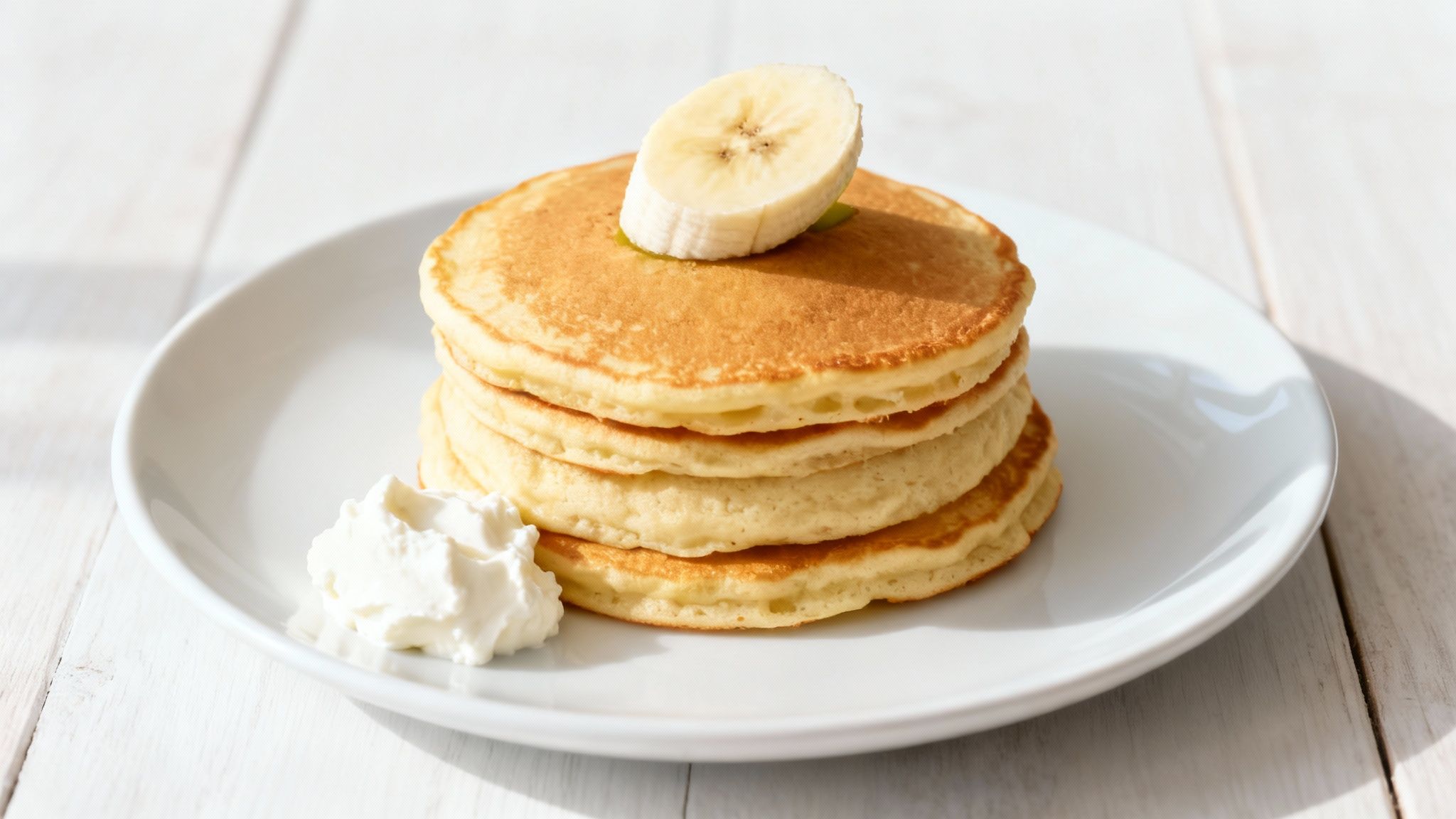 Eine Nahaufnahme von perfekt gestapelten Bananen-Protein-Pancakes mit Beeren als Topping.