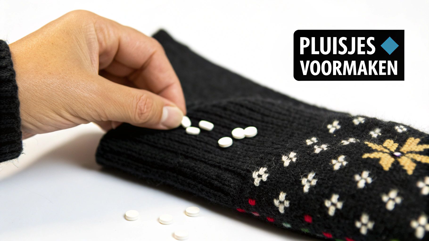 Een hand legt witte pilletjes op een zwarte gebreide mouw met fair isle patroon, om pluisjes te simuleren. Tekst: PLUISJES VOORMAKEN.