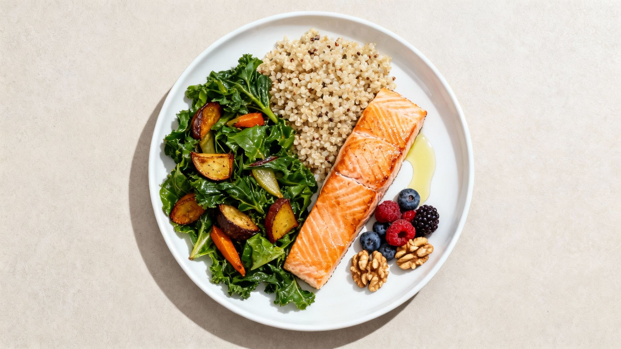 A healthy plate featuring grilled salmon, quinoa, sauteed kale, roasted vegetables, berries, and walnuts.