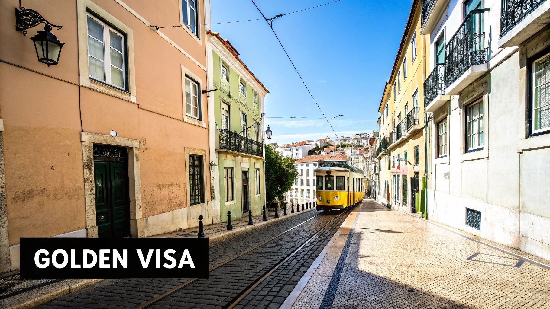 A classic yellow tram on a cobbled street in Lisbon, Portugal, flanked by colorful historic buildings under a clear blue sky, with "GOLDEN VISA" text.