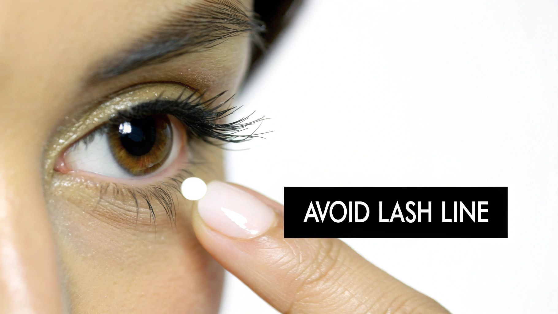 Close-up of a finger with a white dot near a person's lower eye, with text "AVOID LASH LINE".