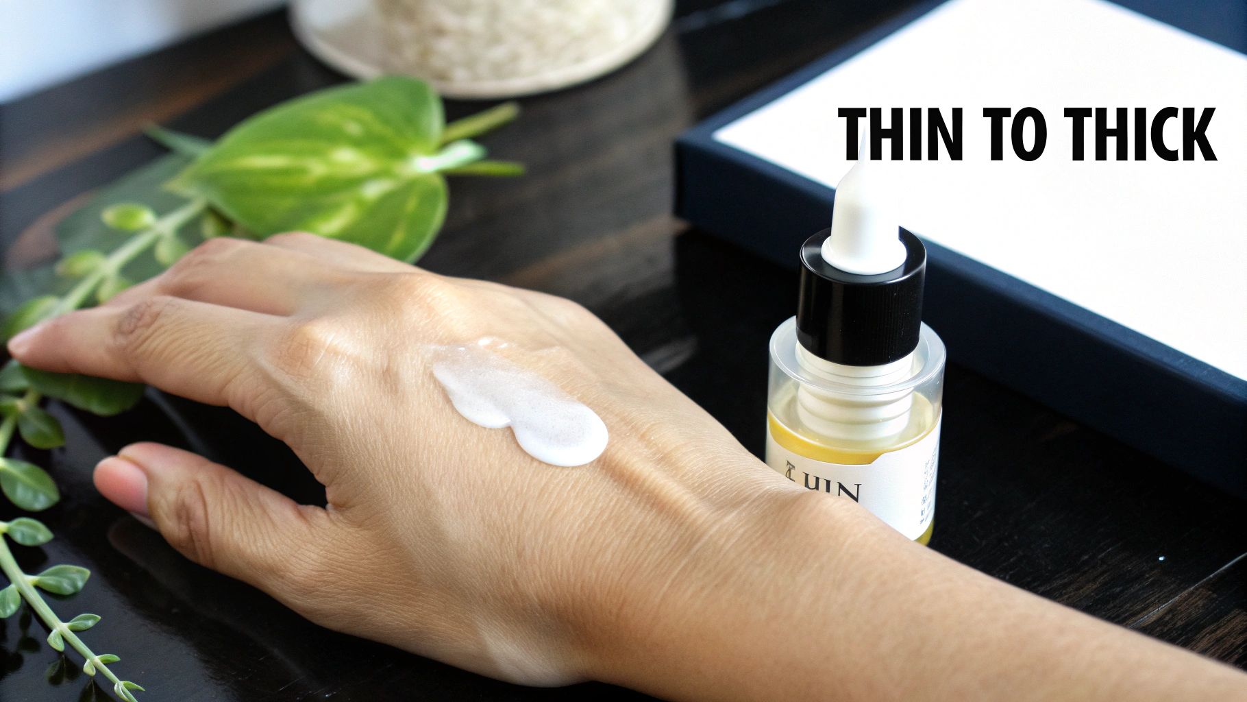A hand with white cream demonstrating application, alongside a serum bottle and 'THIN TO THICK' text.