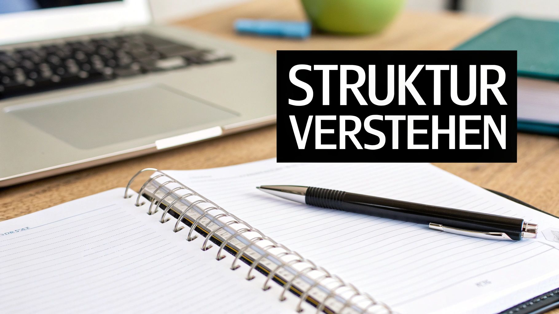 Ein Laptop, ein offenes Notizbuch mit einem Stift und eine Textbox mit „STRUKTUR VERSTEHEN“ auf einem Holztisch.