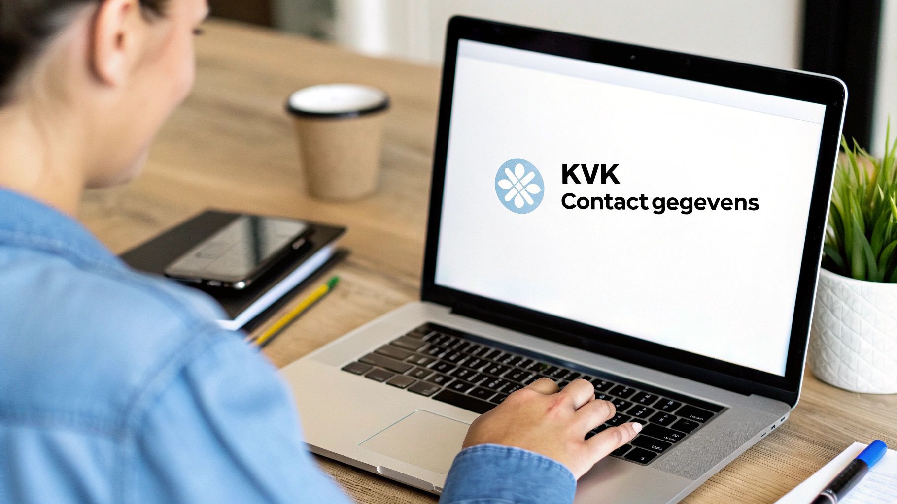 Persoon werkt op laptop met KVK contactgegevens scherm, professionele werkruimte met koffie en plant